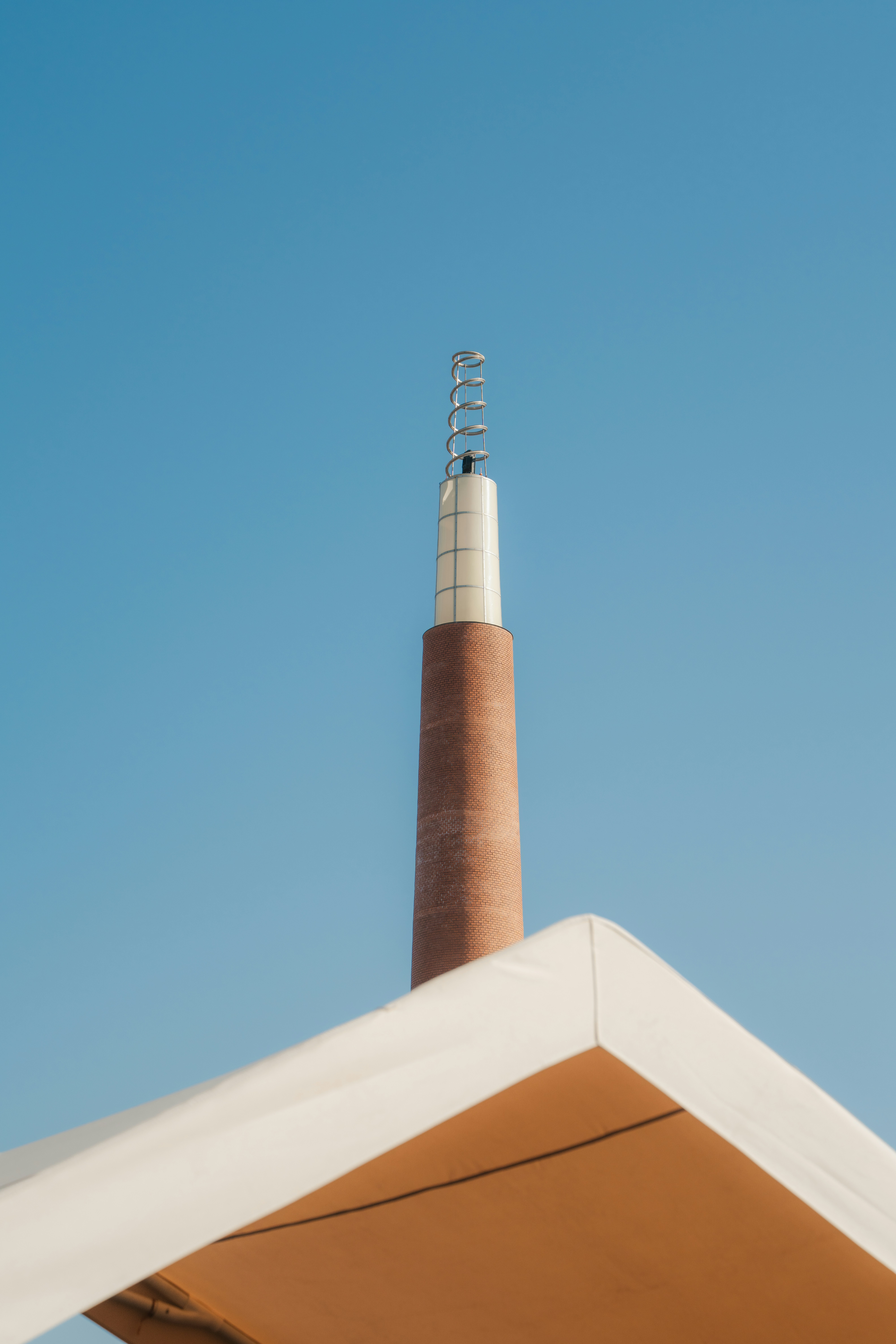 Tall brick tower with antenna against clear blue sky