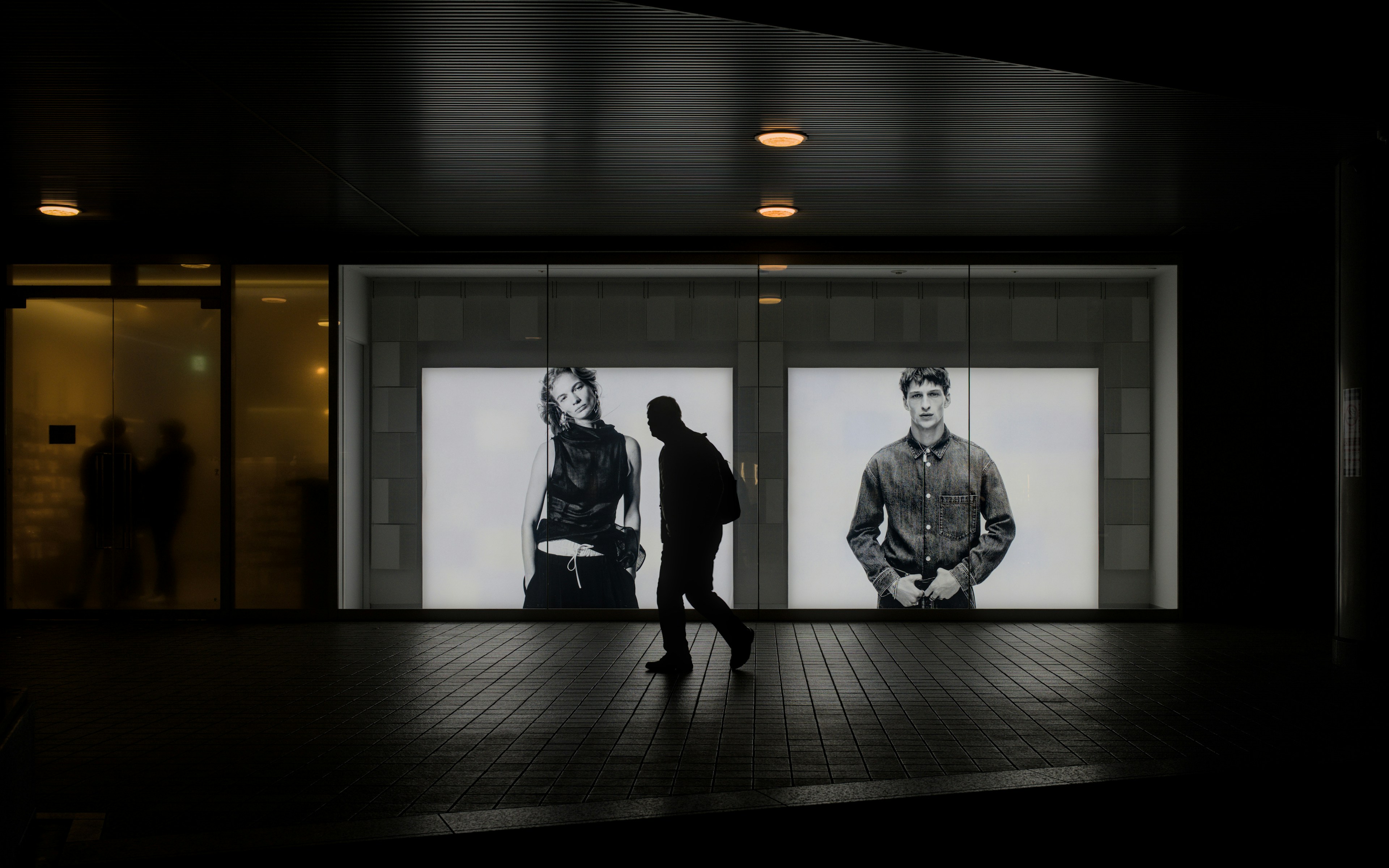 Man walks past storefront with large fashion displays