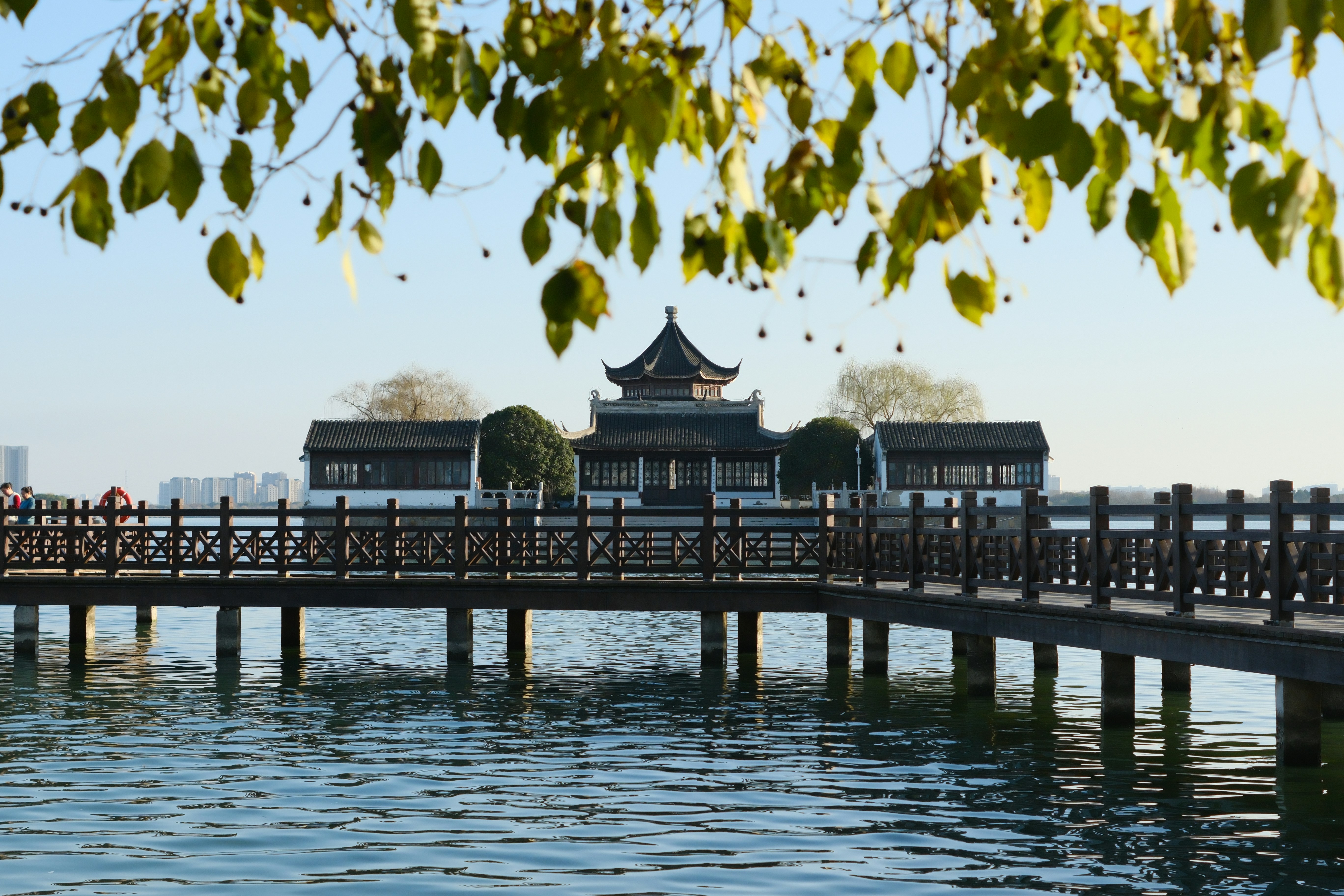 Traditional building across a calm lake with wooden bridge