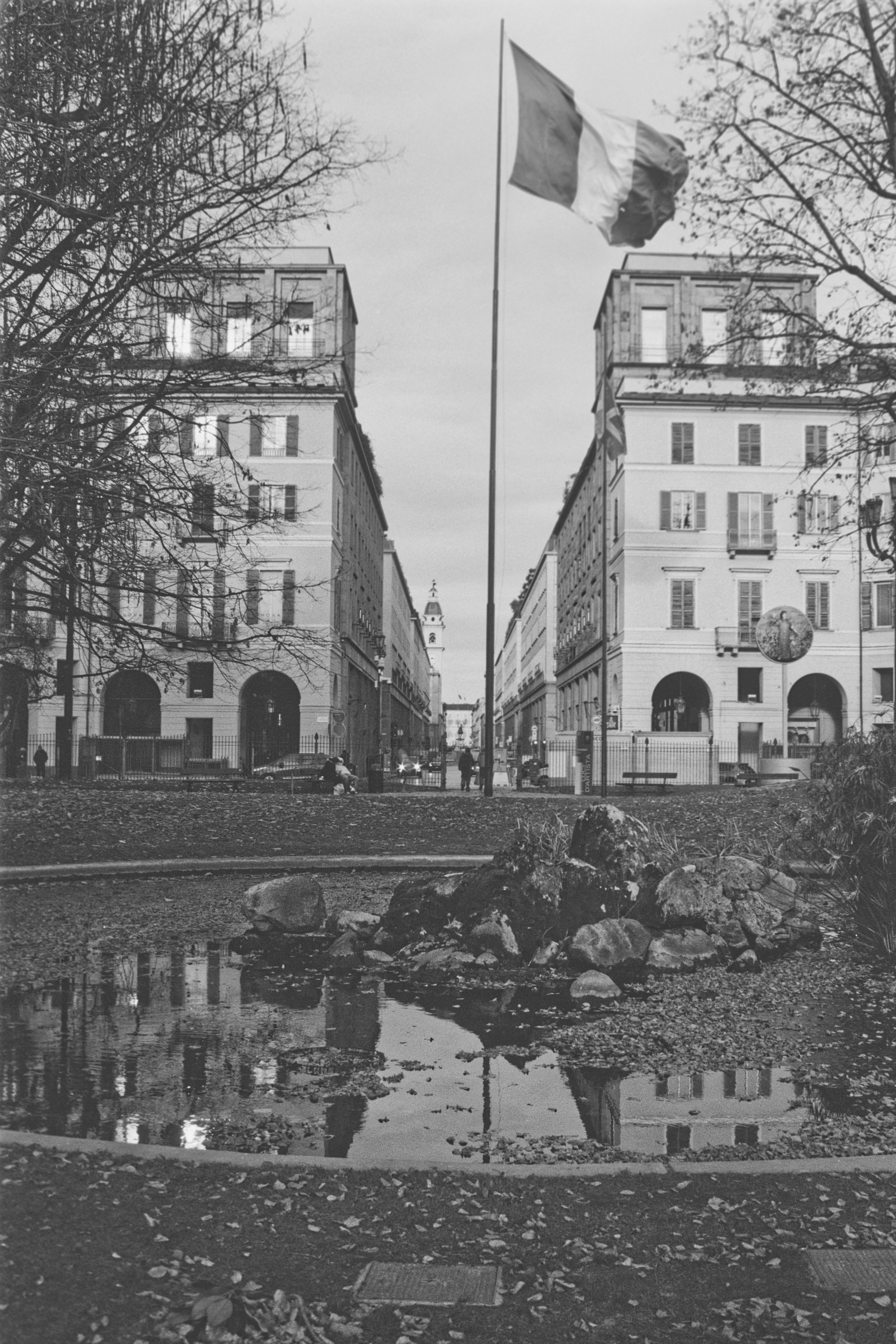 Die italienische Flagge weht über einer Stadtstraße mit Gebäuden.