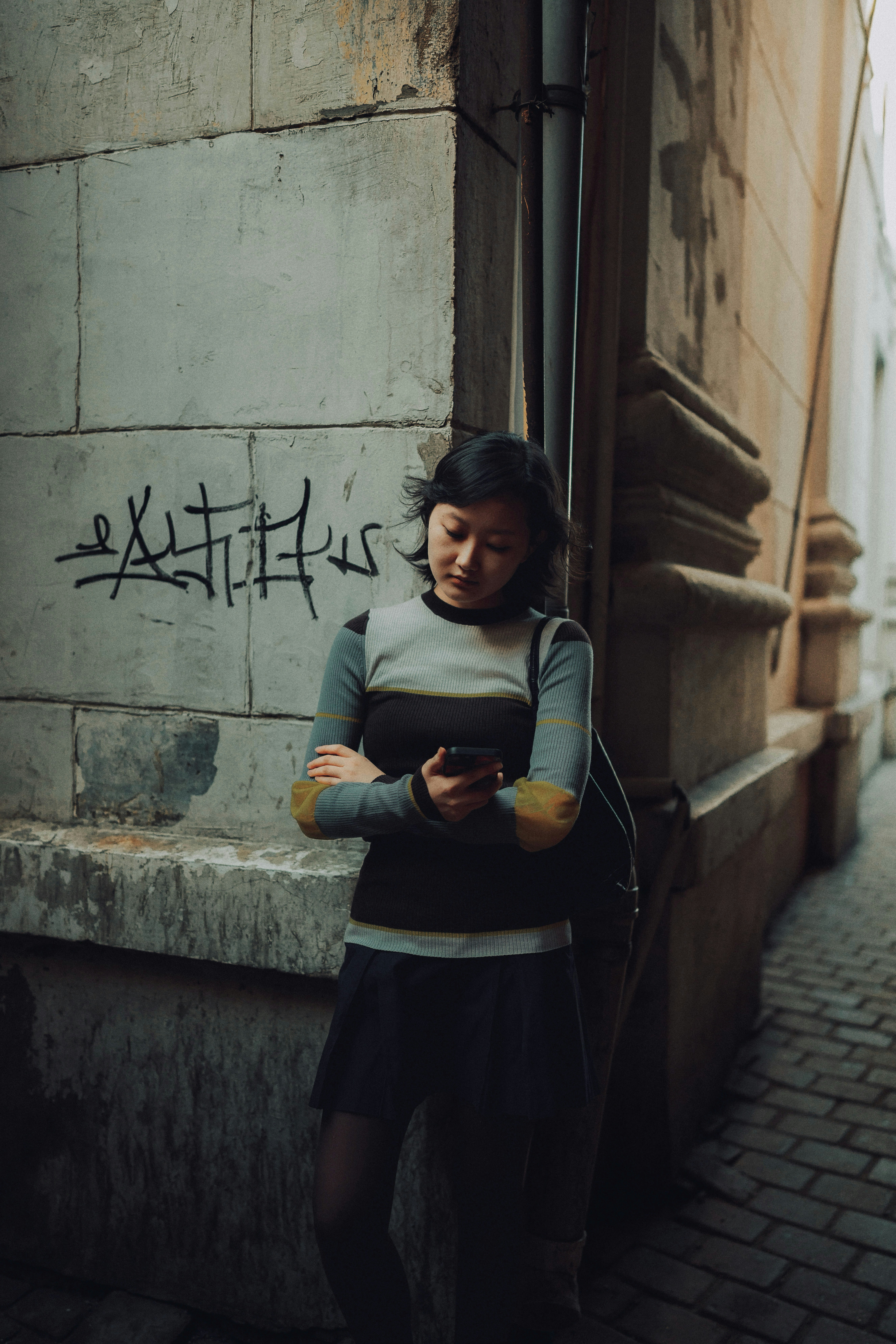 Young woman looking at phone on city street.