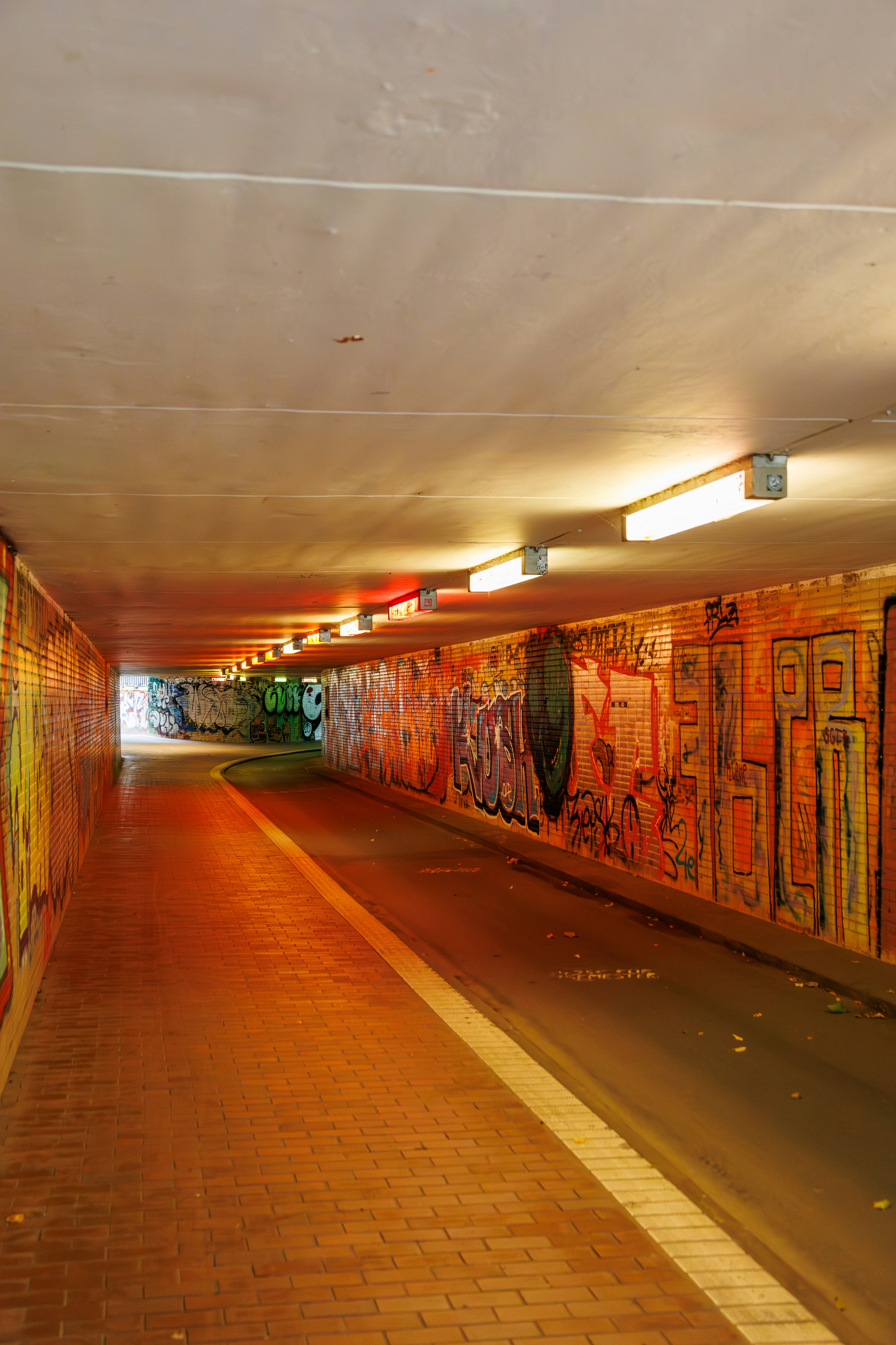 A tunnel with colorful graffiti art and overhead lights.