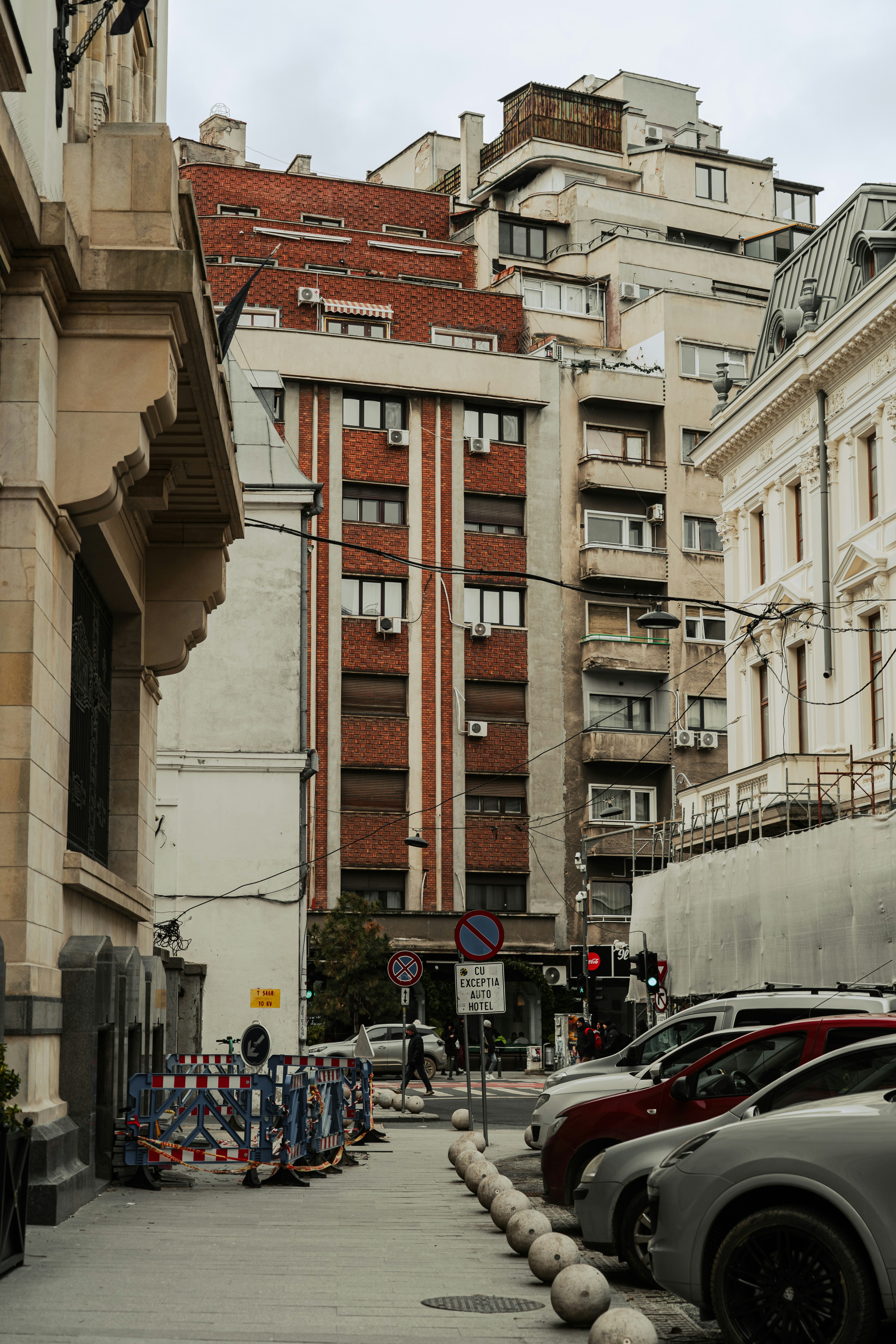 Row of parked cars on a city street with buildings.