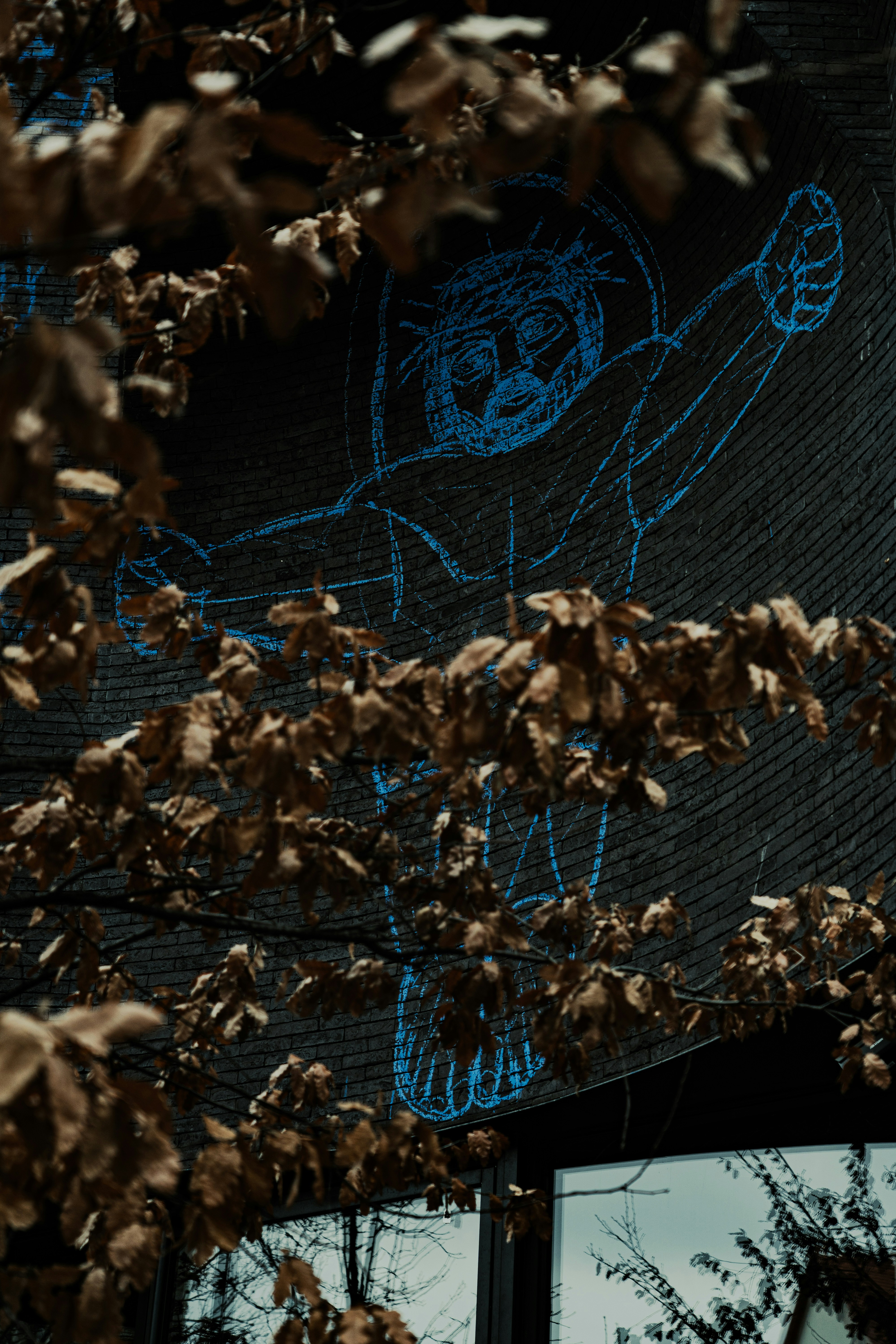 Chalk drawing of a person on a wall behind leaves