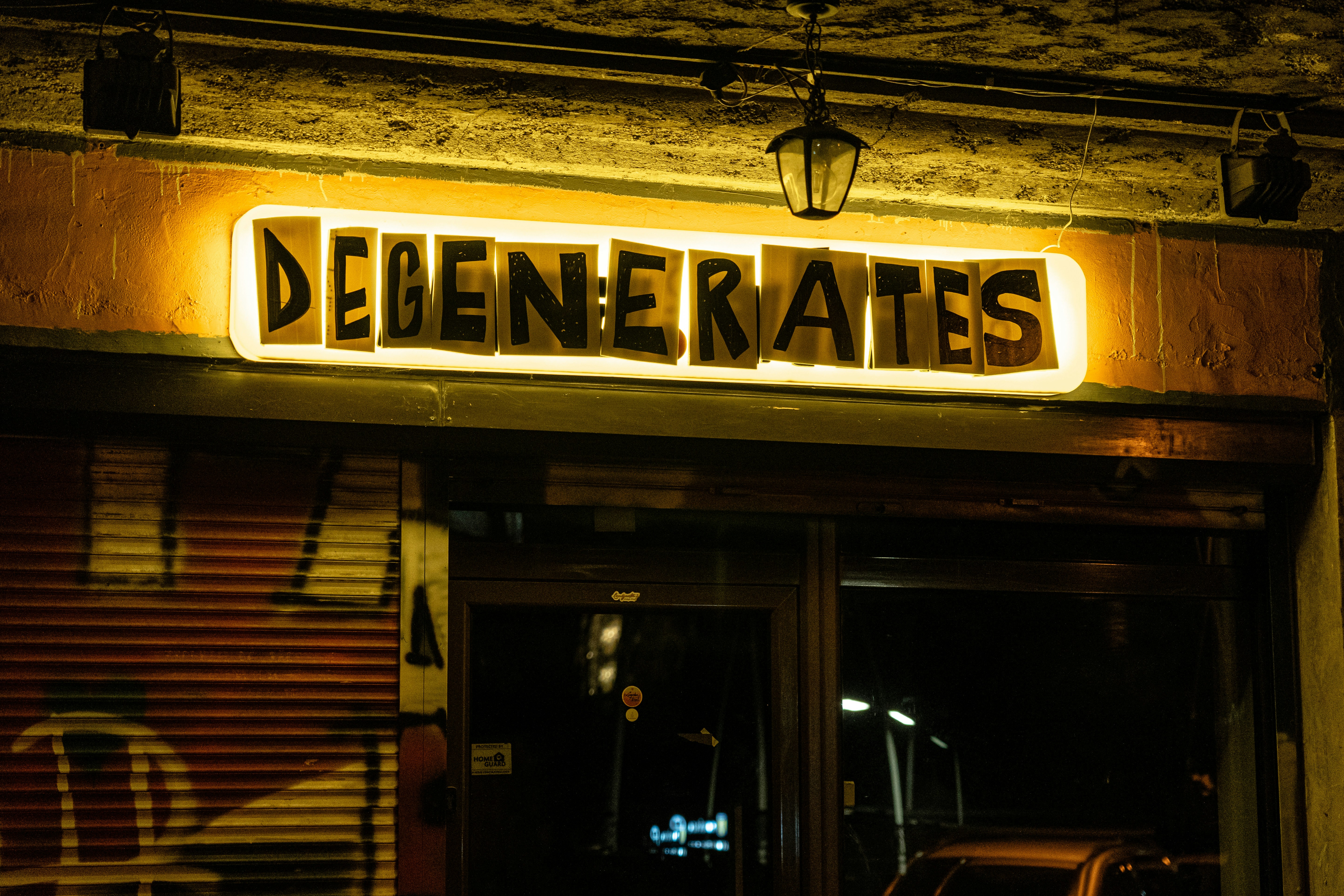 A neon sign reads degenerates above a doorway.