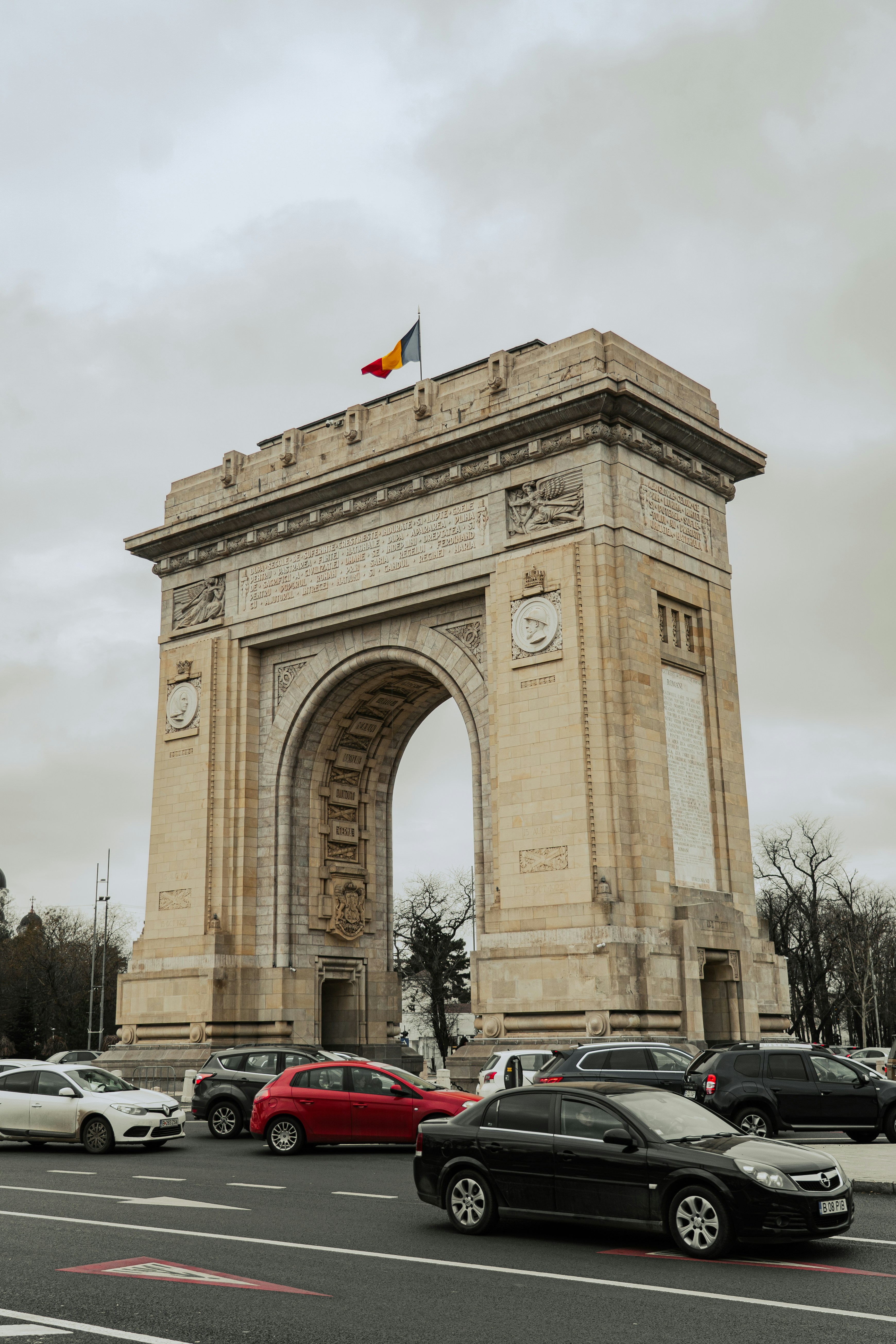 The arcul de triumf in bucharest with cars driving by.