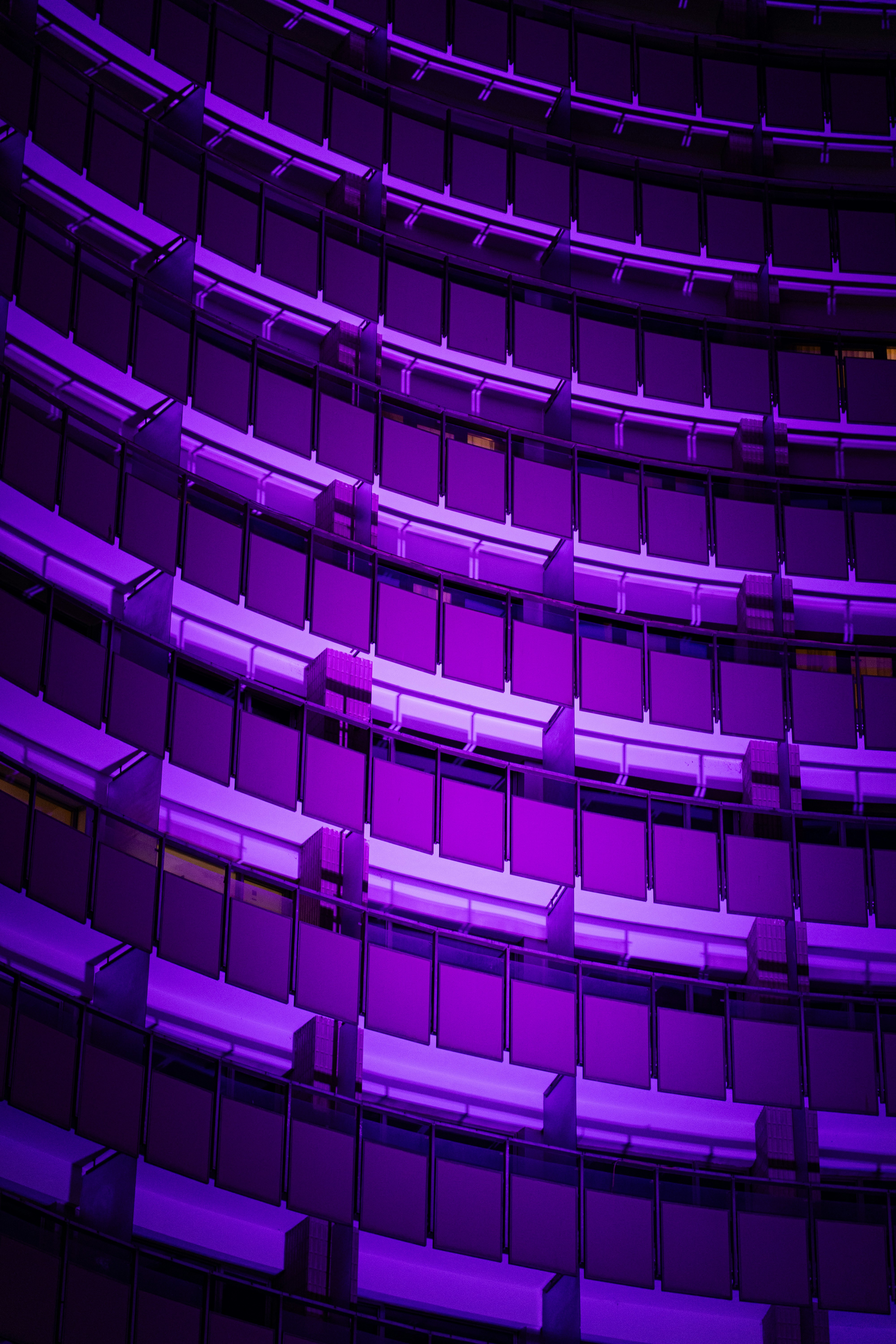 Curved building facade illuminated with purple lights.