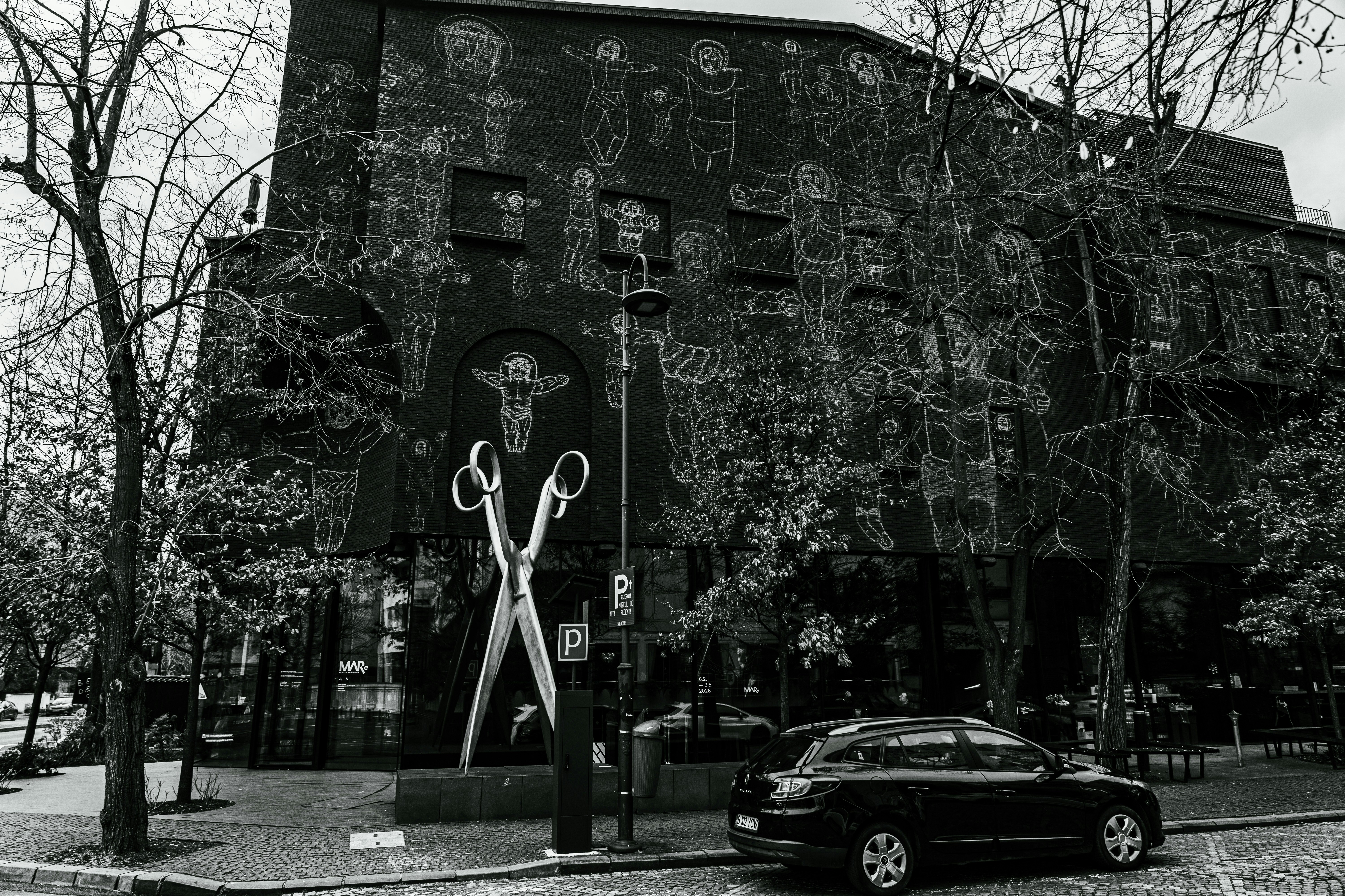 Building with large scissors mural and trees
