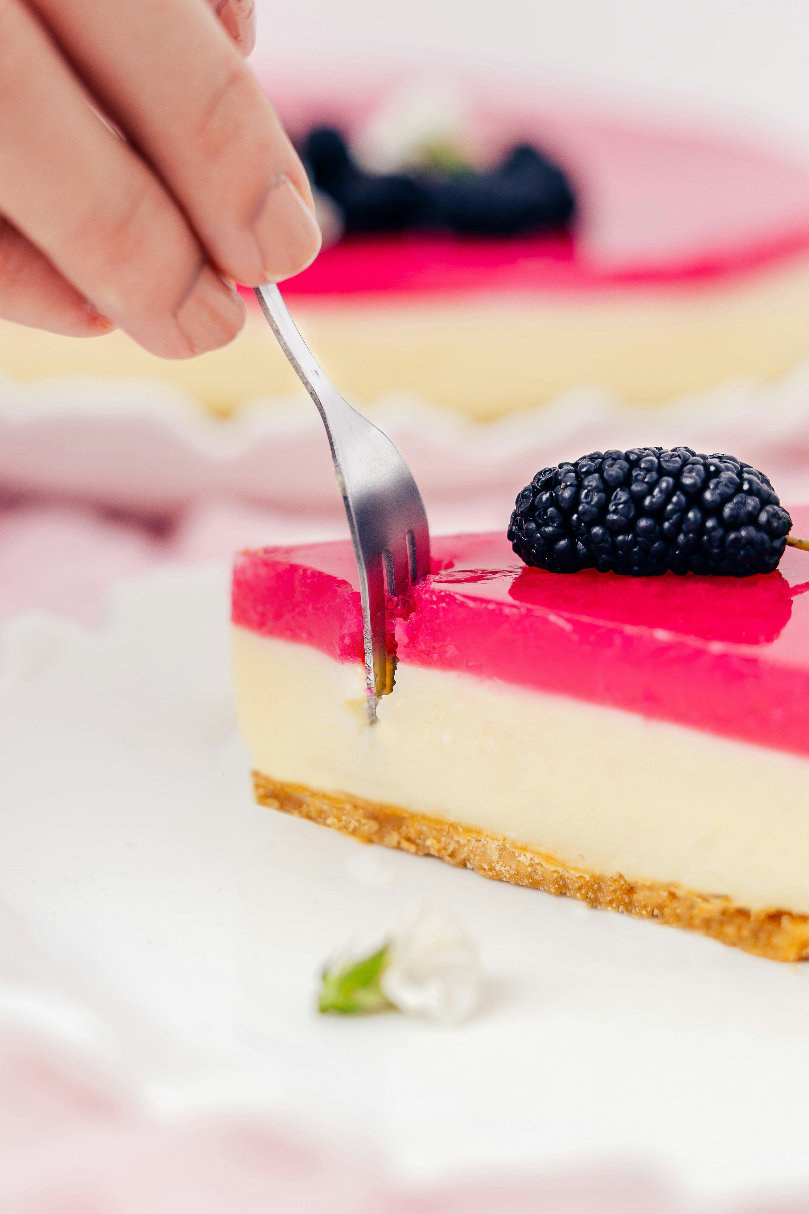 Fork cutting into a slice of berry cheesecake