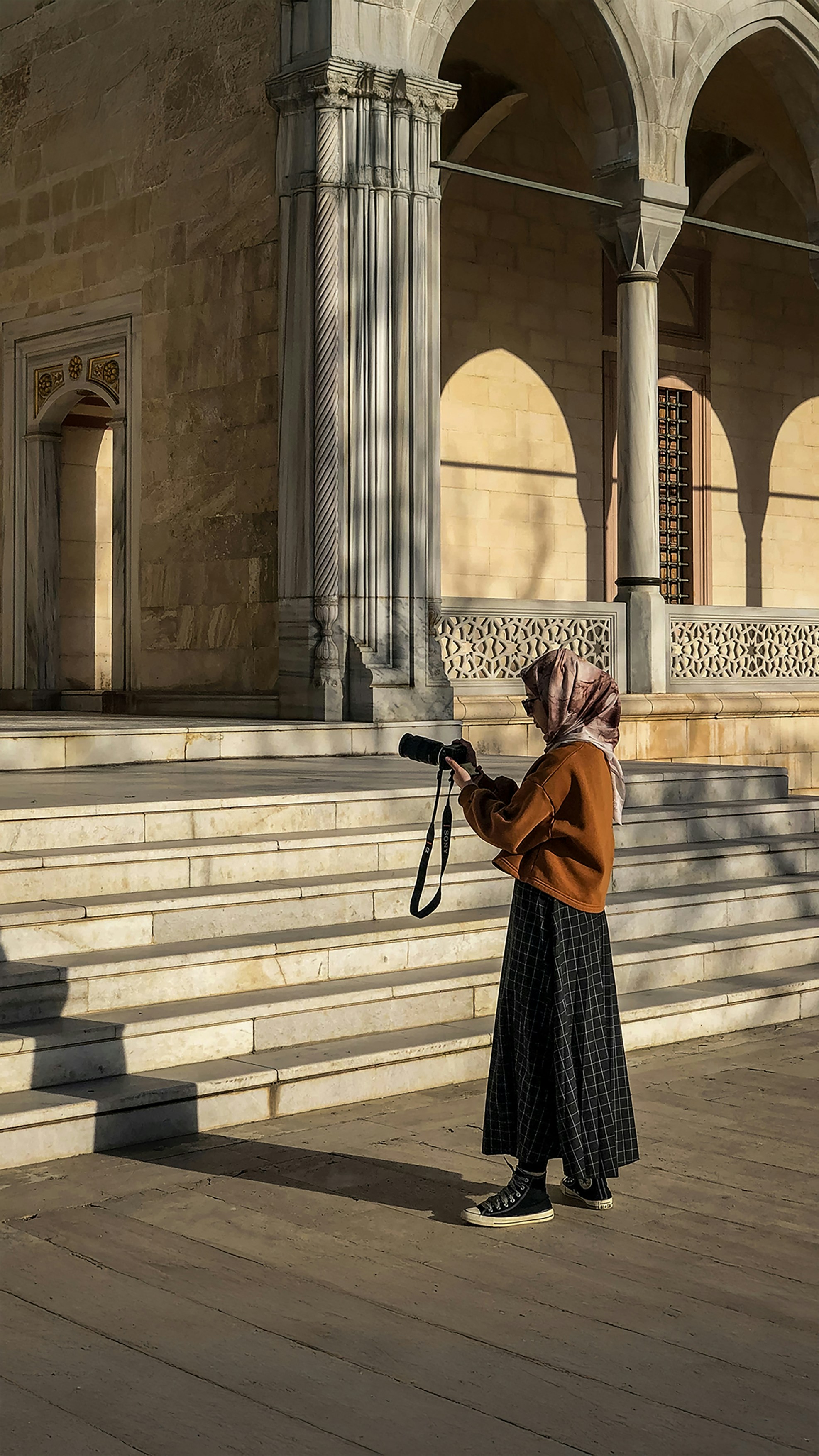 Woman in hijab photographing a historic building with her camera