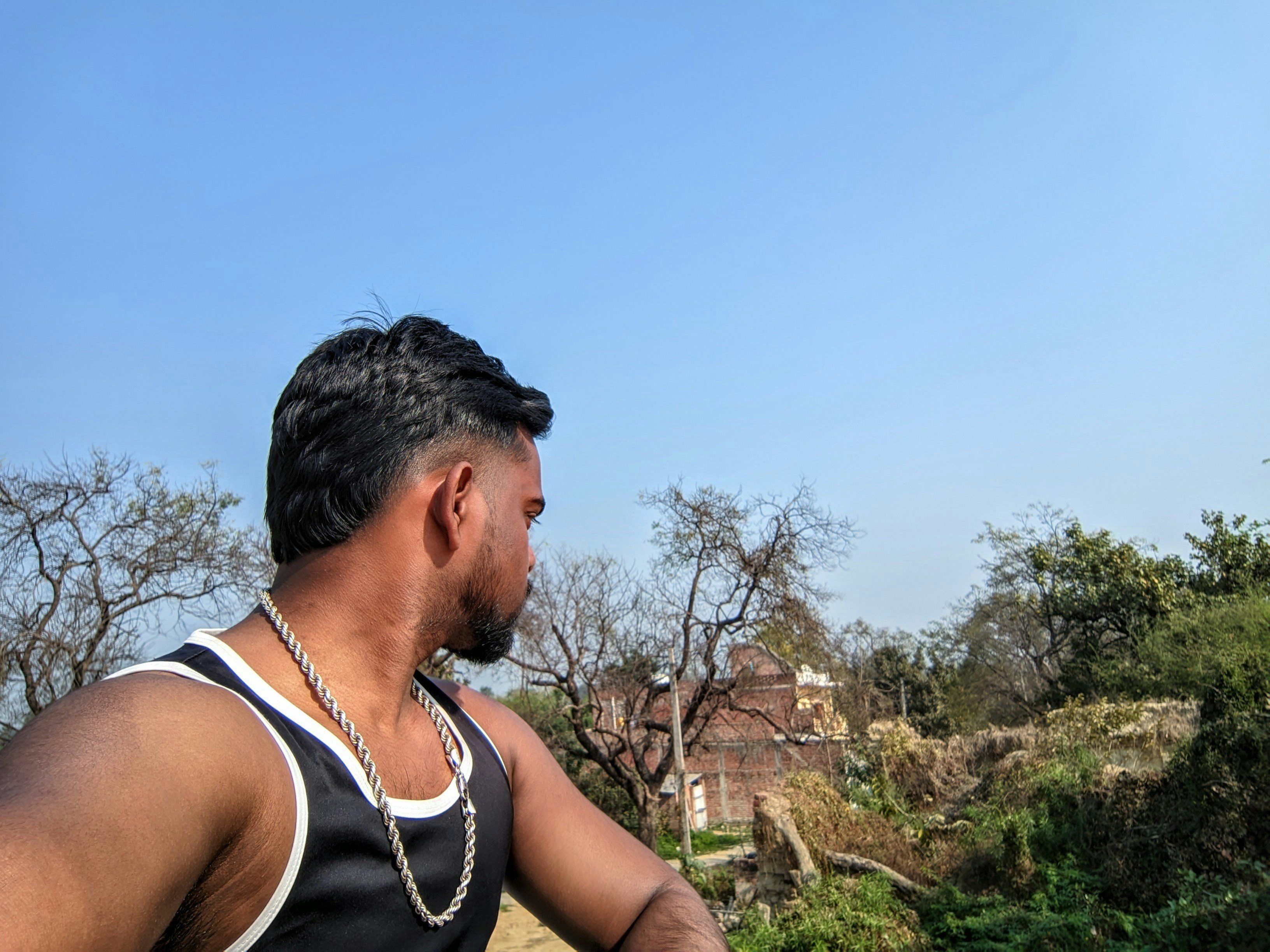 Pria dengan tank top memandang jauh dari kamera di luar ruangan