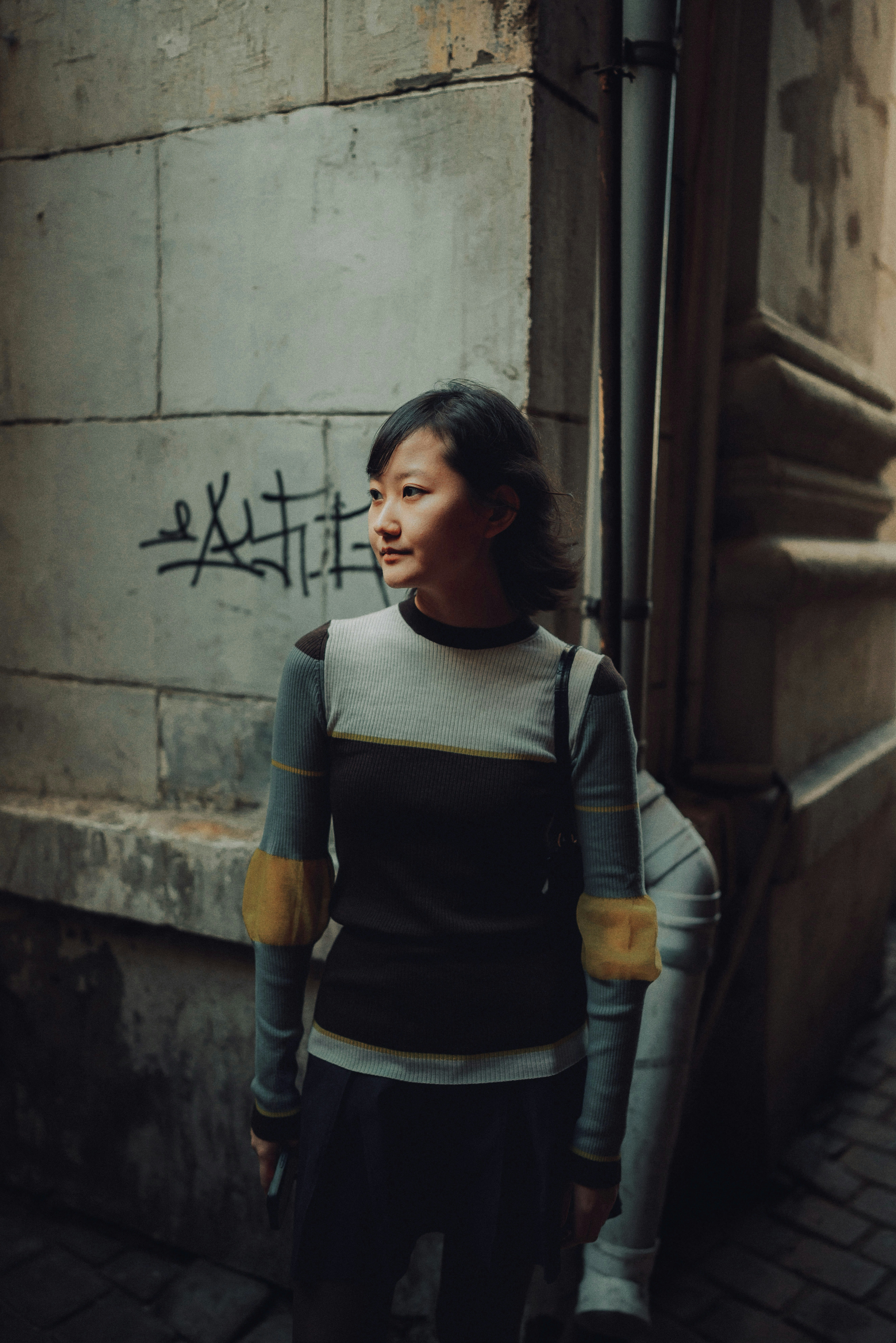 Young woman standing on a cobblestone street.