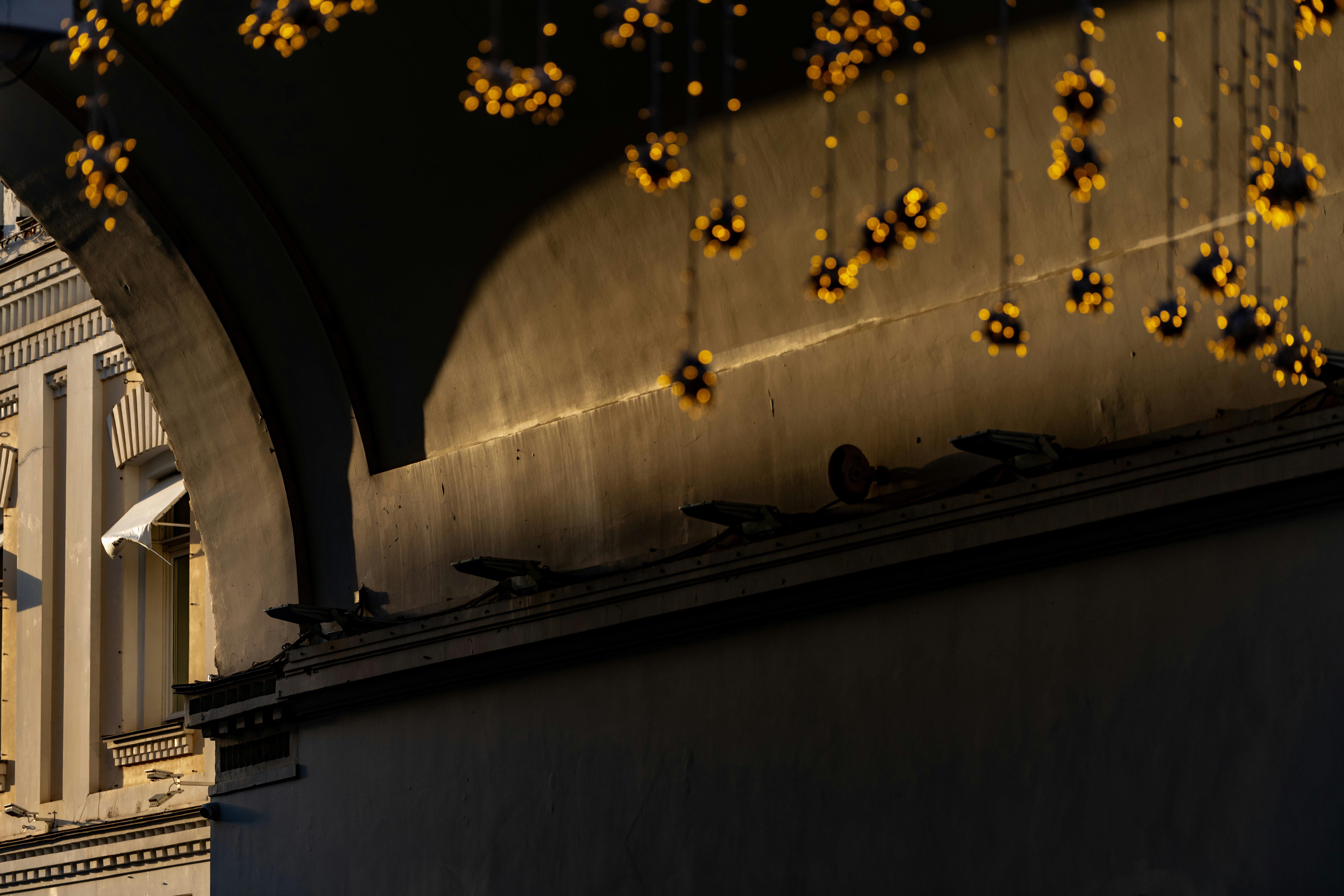 Luzes douradas pendem de um arco escuro.