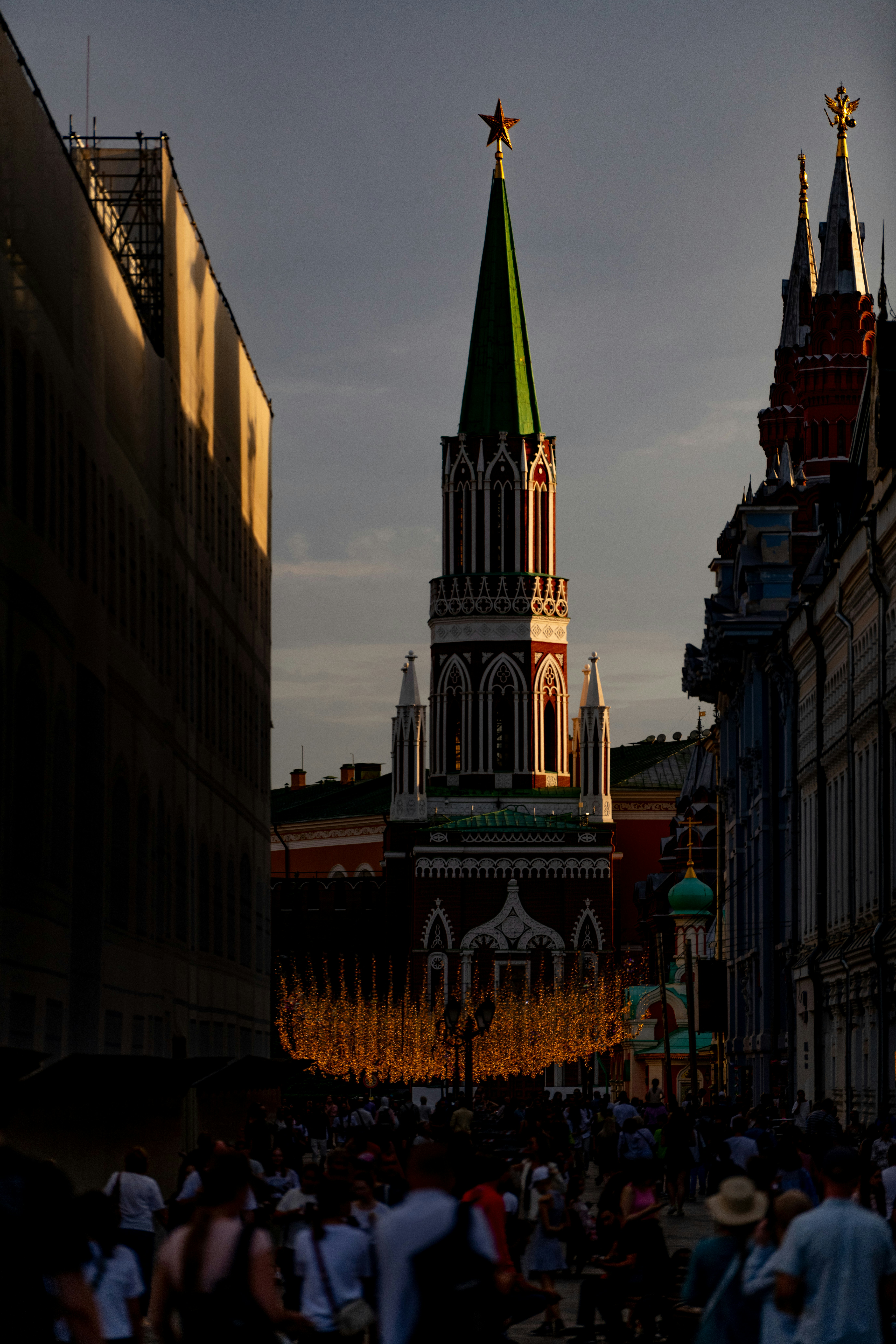 Rua lotada levando a uma torre alta e ornamentada ao pôr do sol