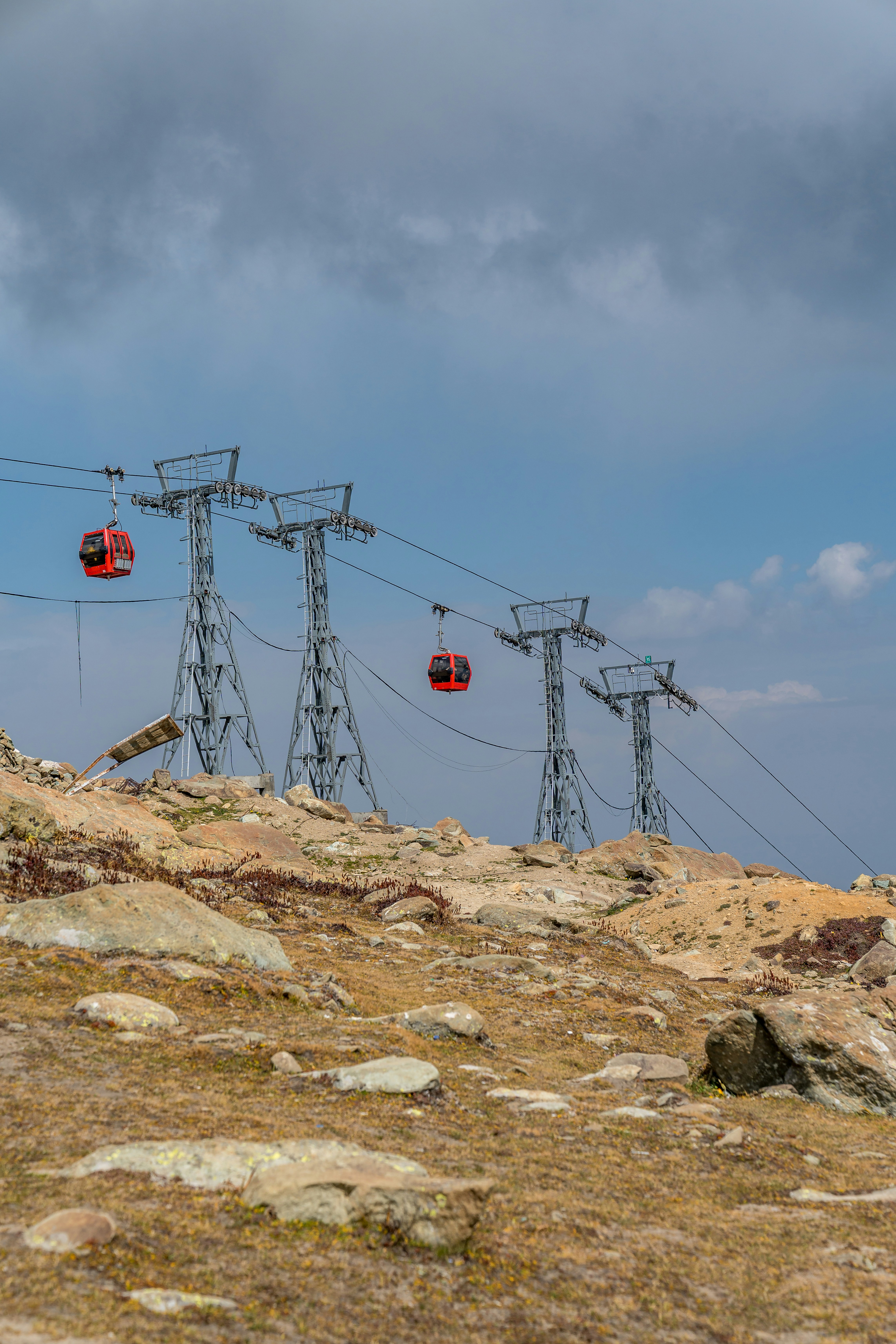 Red cable cars ascend mountain towers under cloudy sky