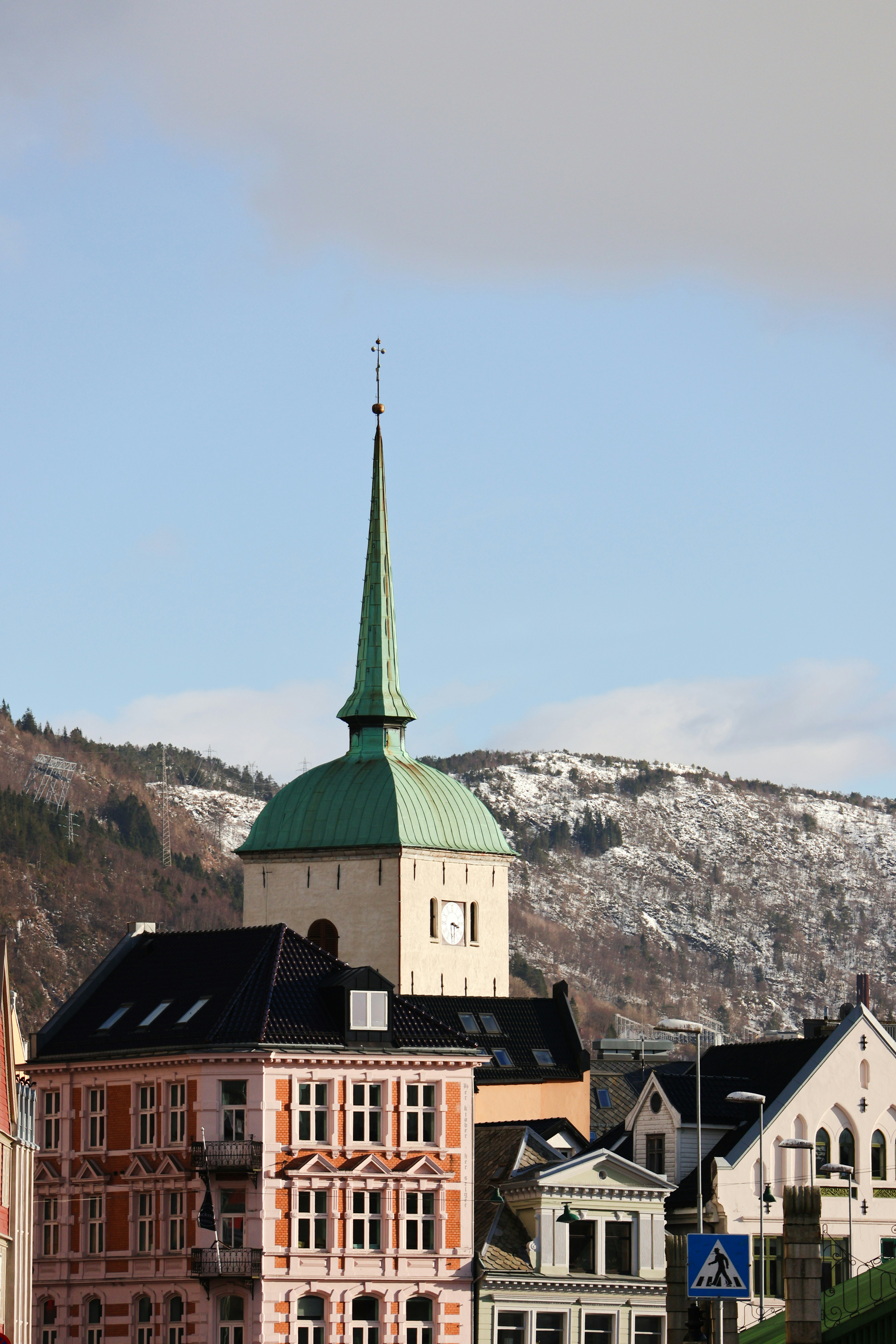 Campanario de la iglesia y edificios con fondo nevado de montaña