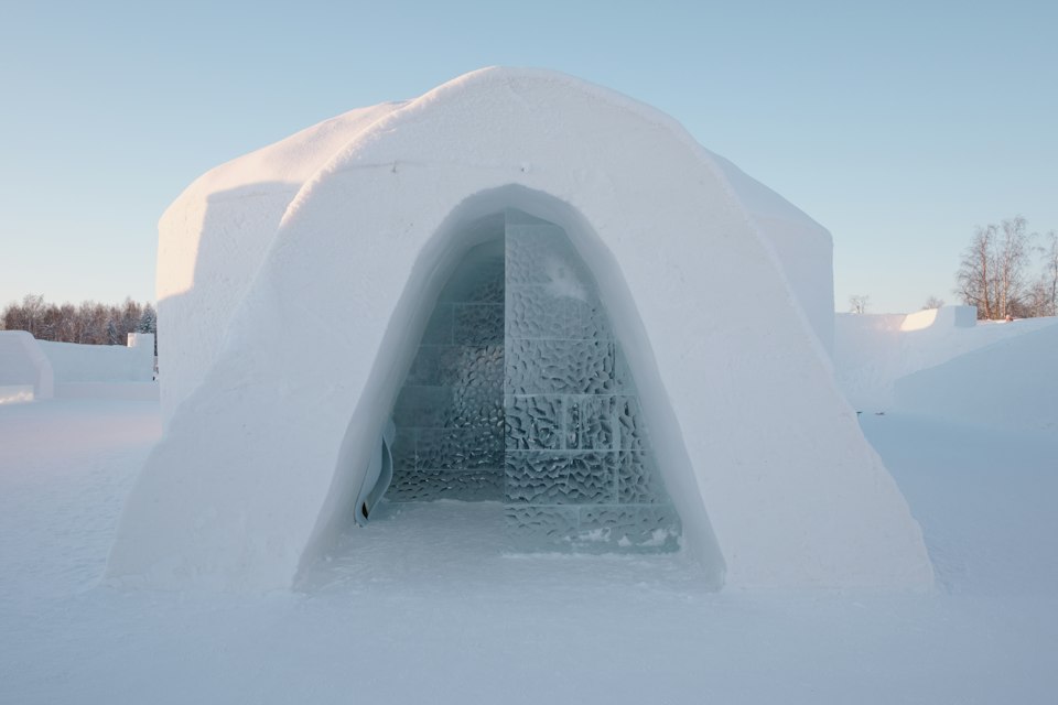 An ice hotel entrance built from snow and ice in a wintry landscape