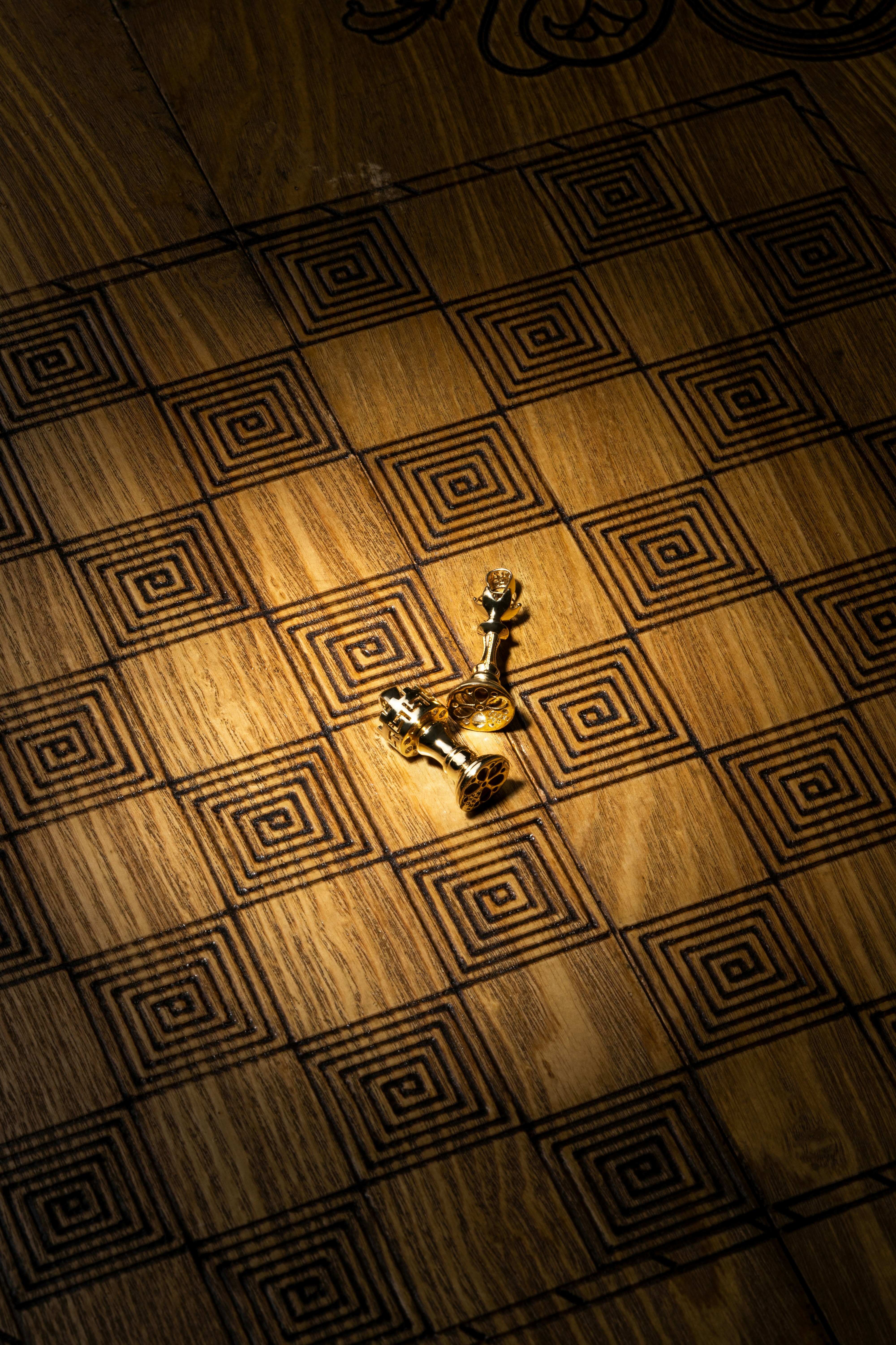 Two golden chess pieces on a wooden board.