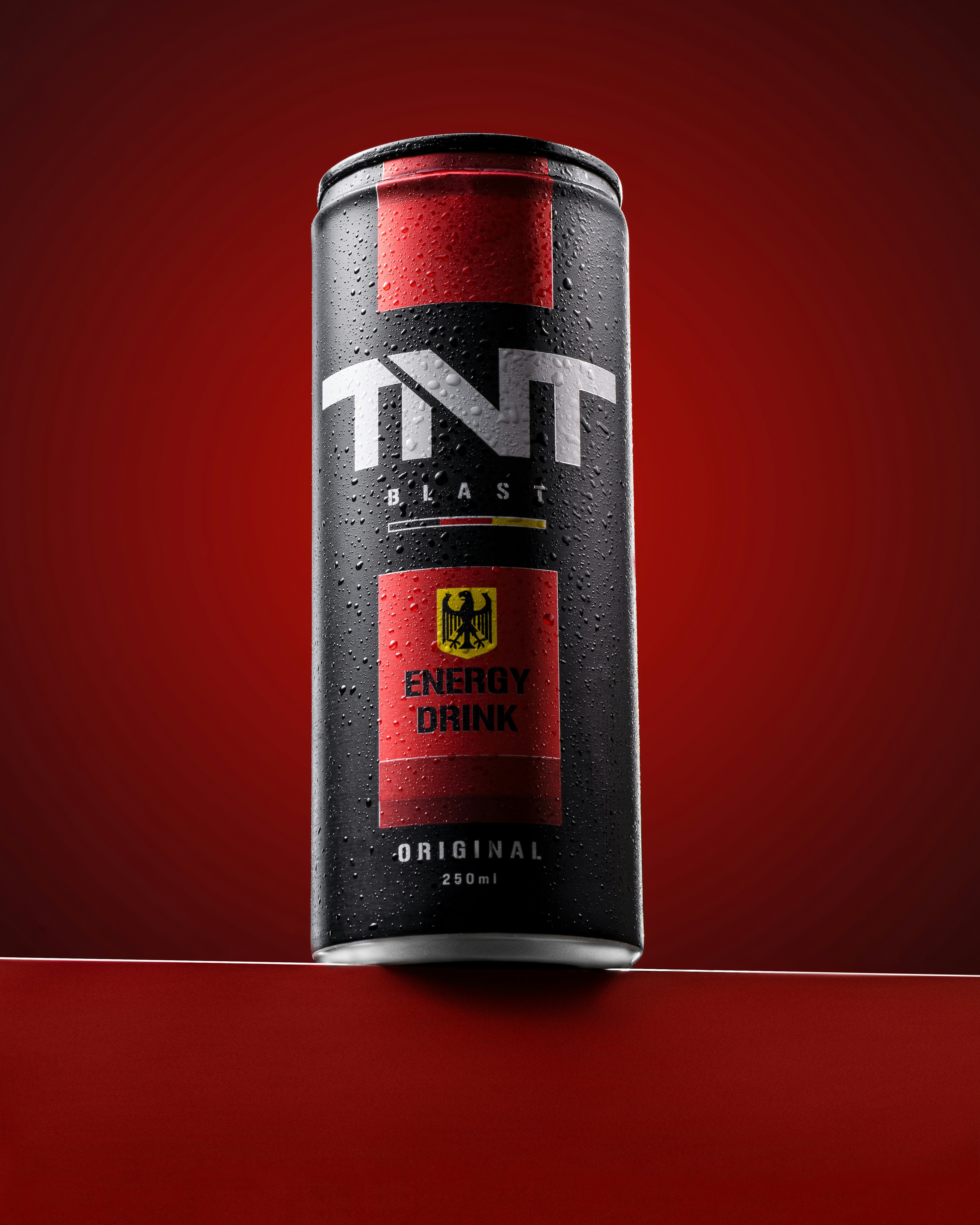 A can of tnt energy drink on a red surface.