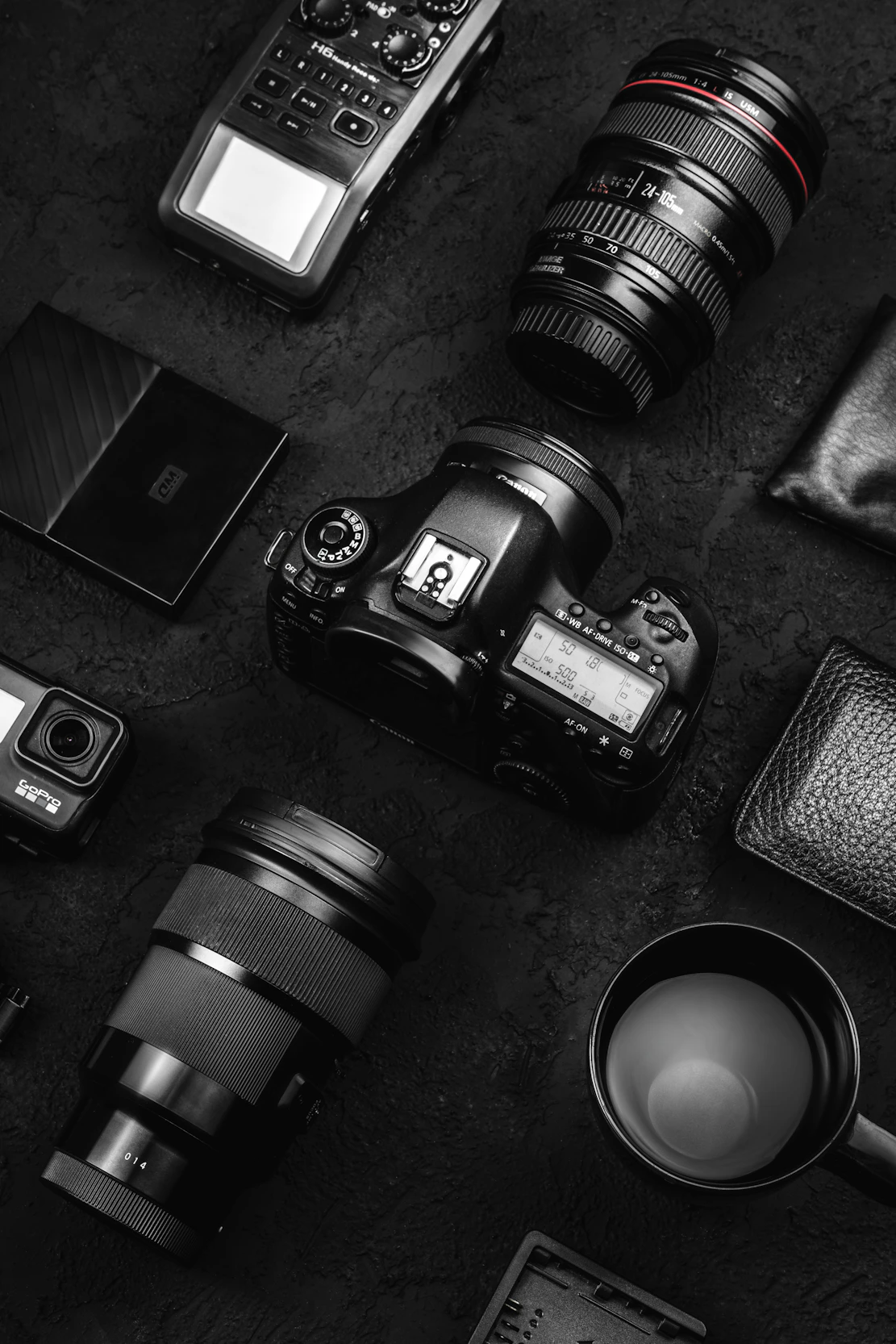 Camera gear and accessories laid out on dark surface.