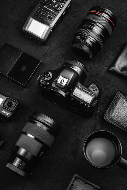 Camera gear and accessories laid out on dark surface.