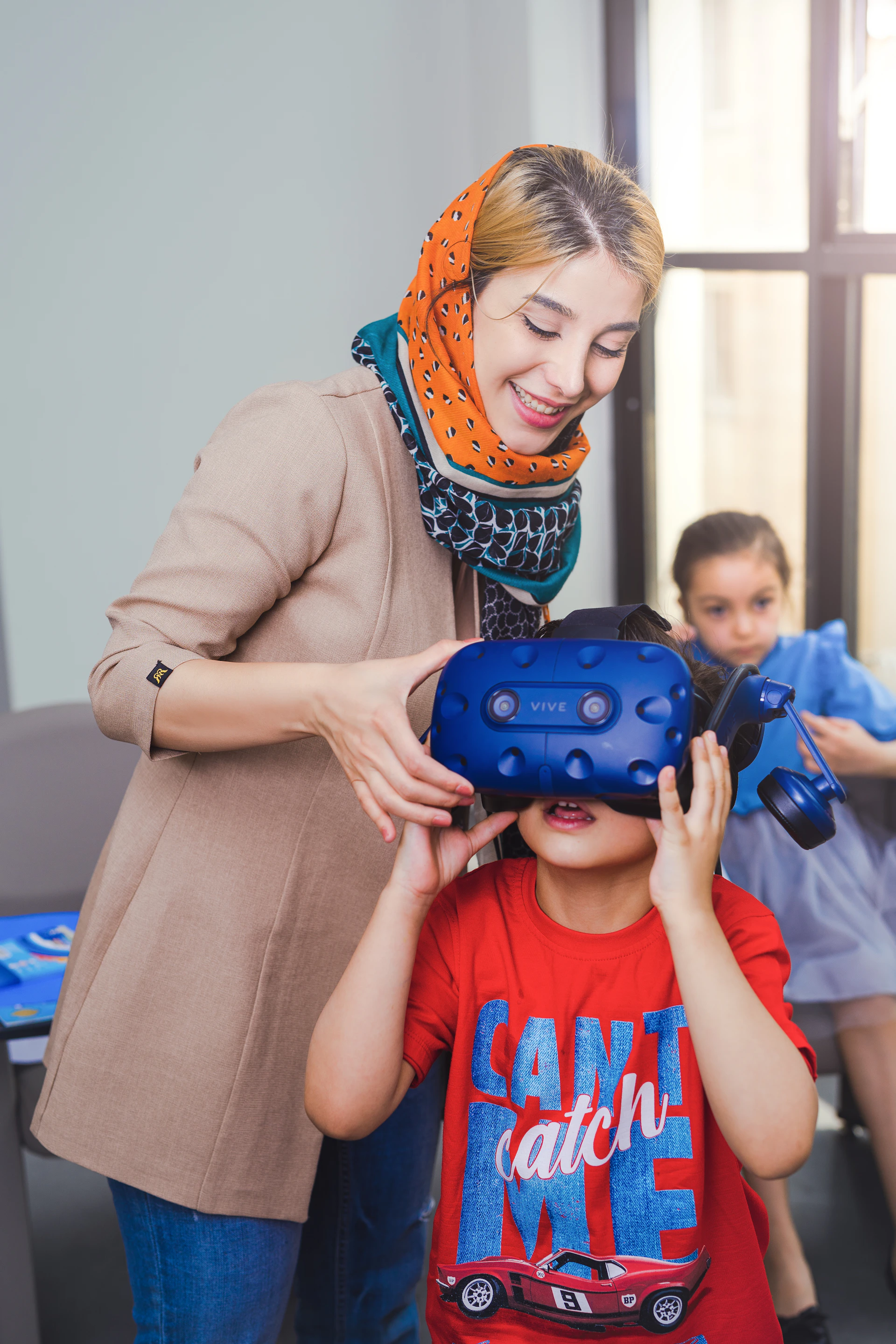 Woman helps child put on virtual reality headset.