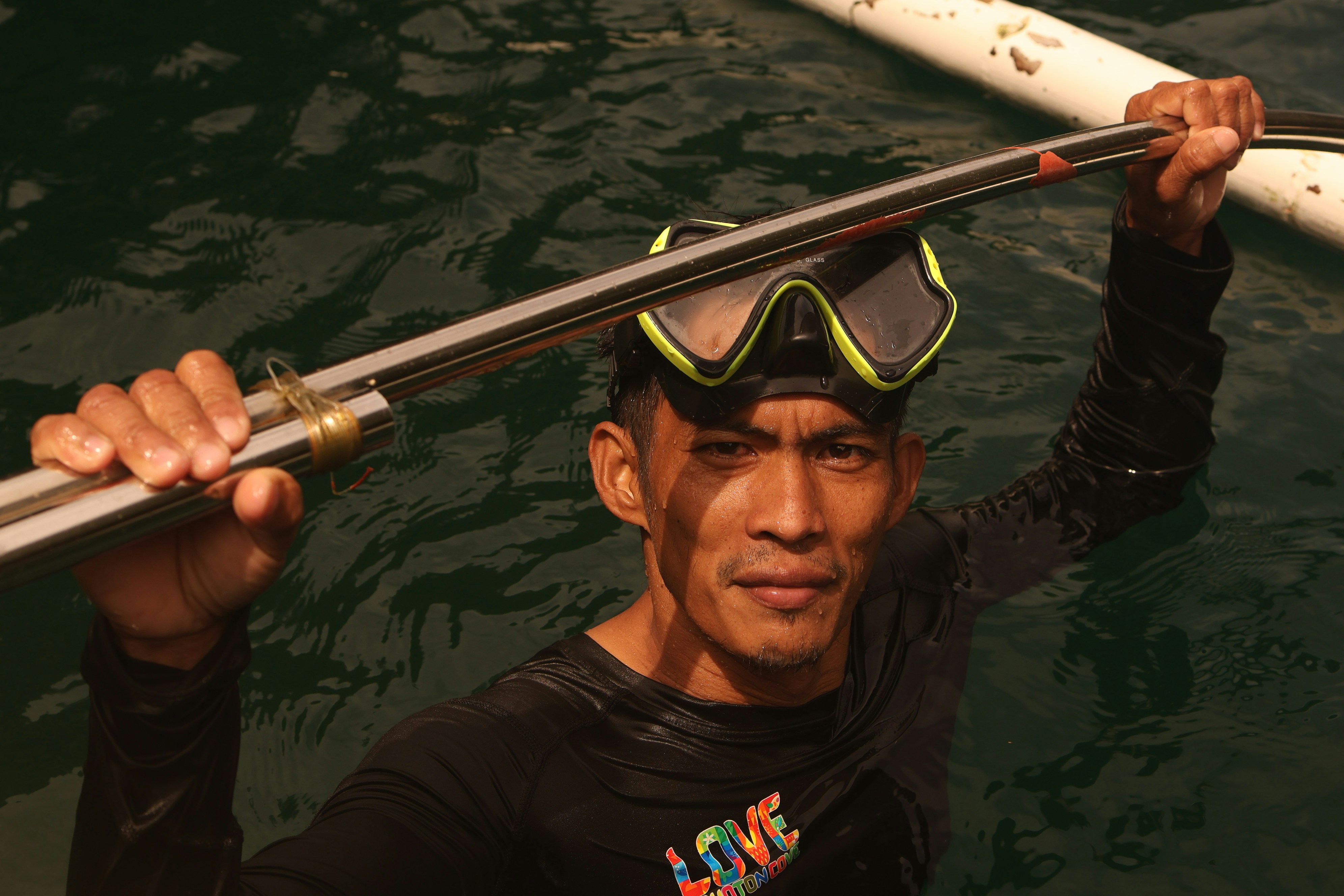 Man in mask holds speargun in dark water