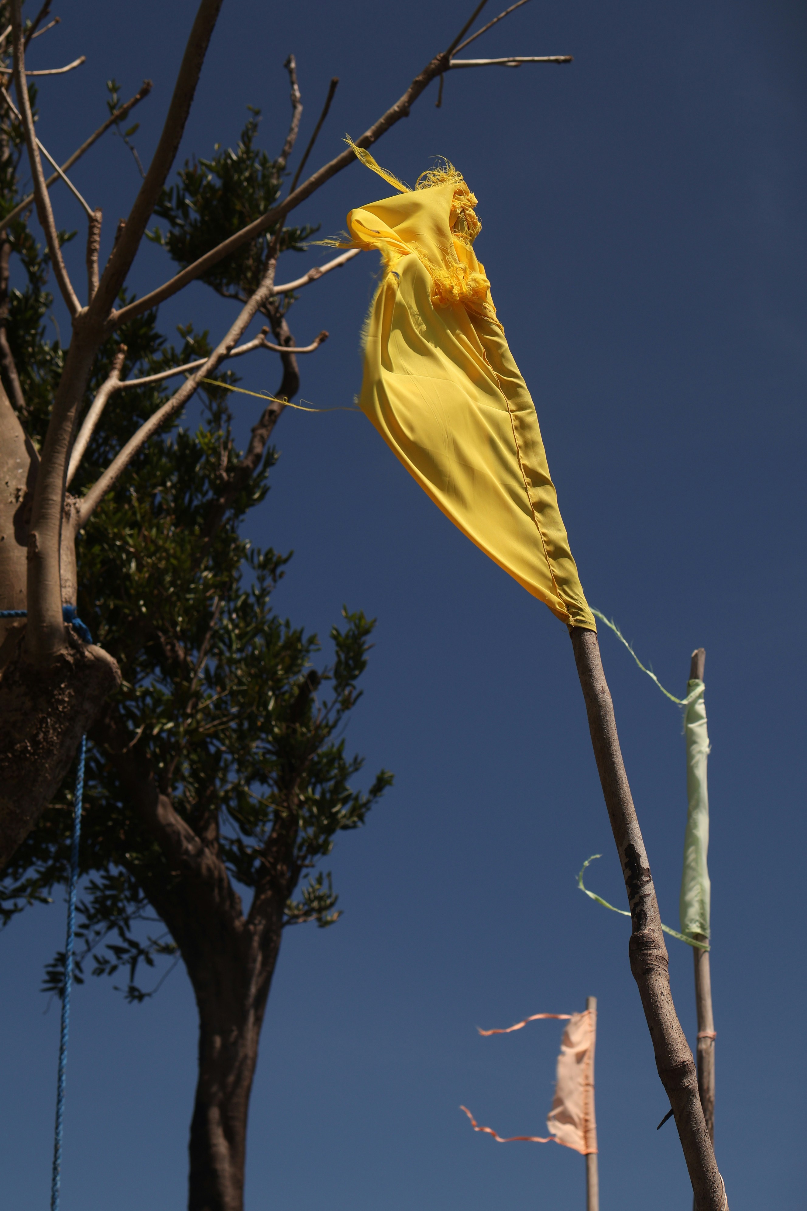 Yellow flag waves on a wooden pole against blue sky