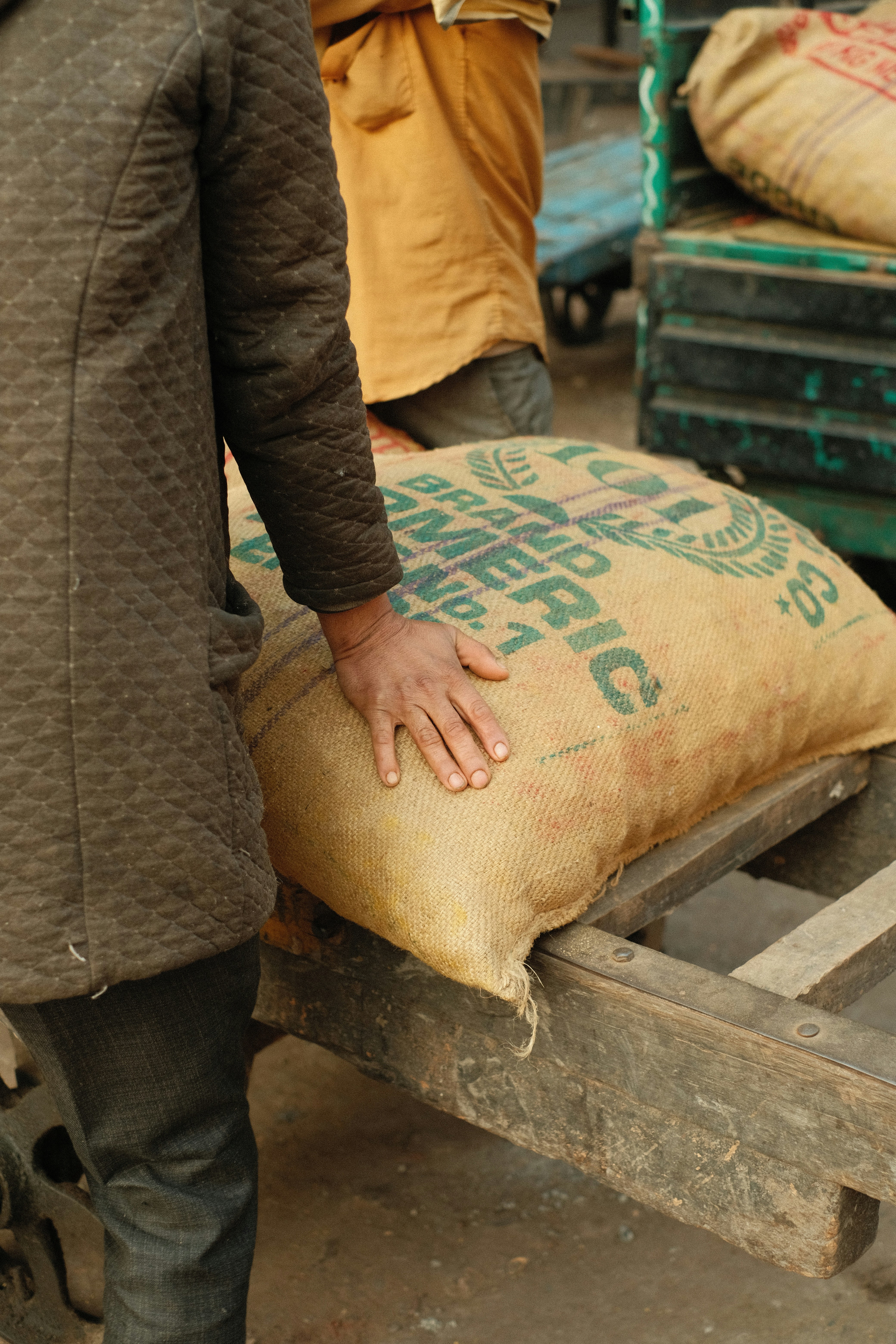 Pessoa carregando um grande saco de estopa em um carrinho