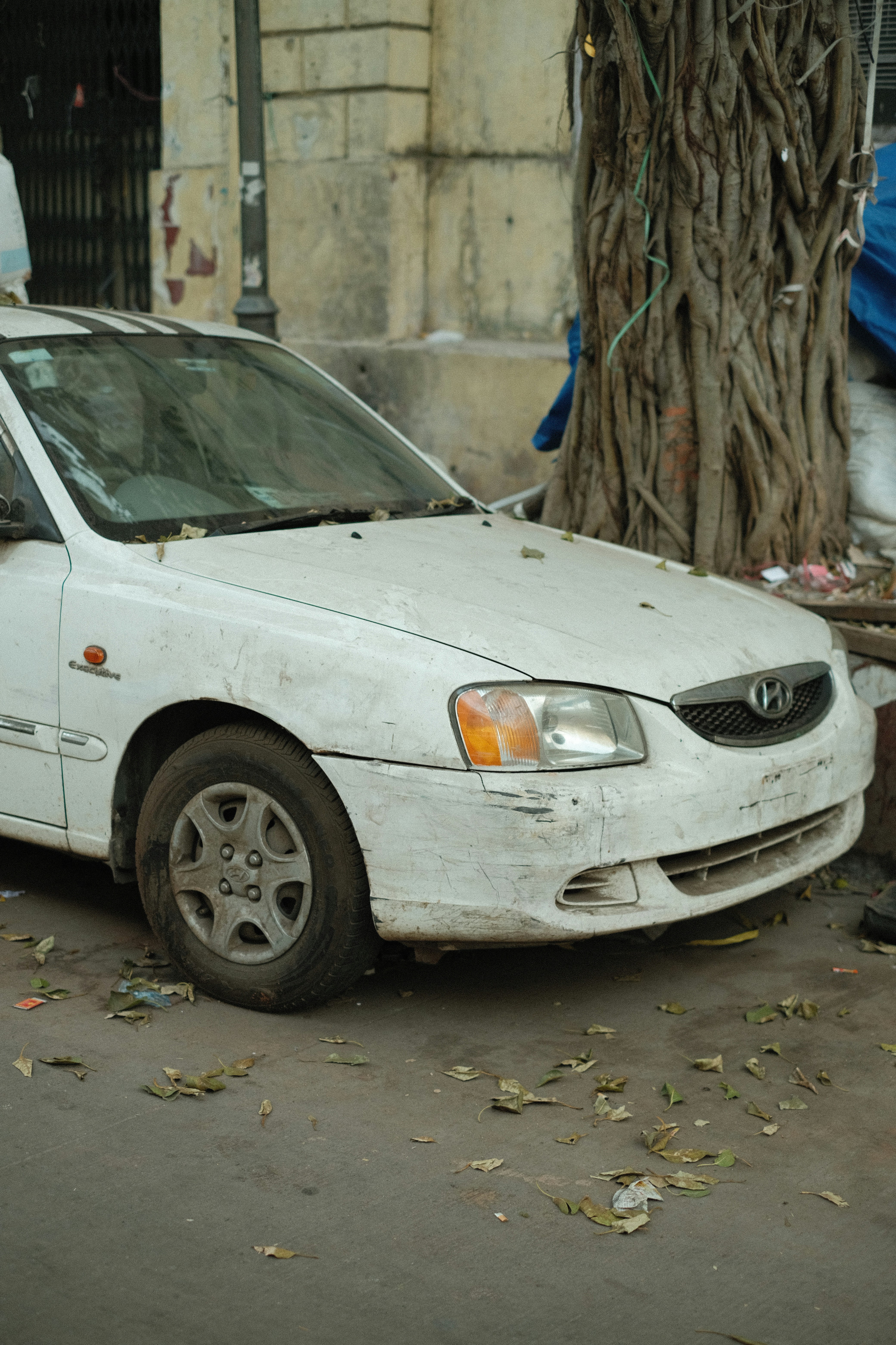 Um carro branco sujo estacionado numa rua.