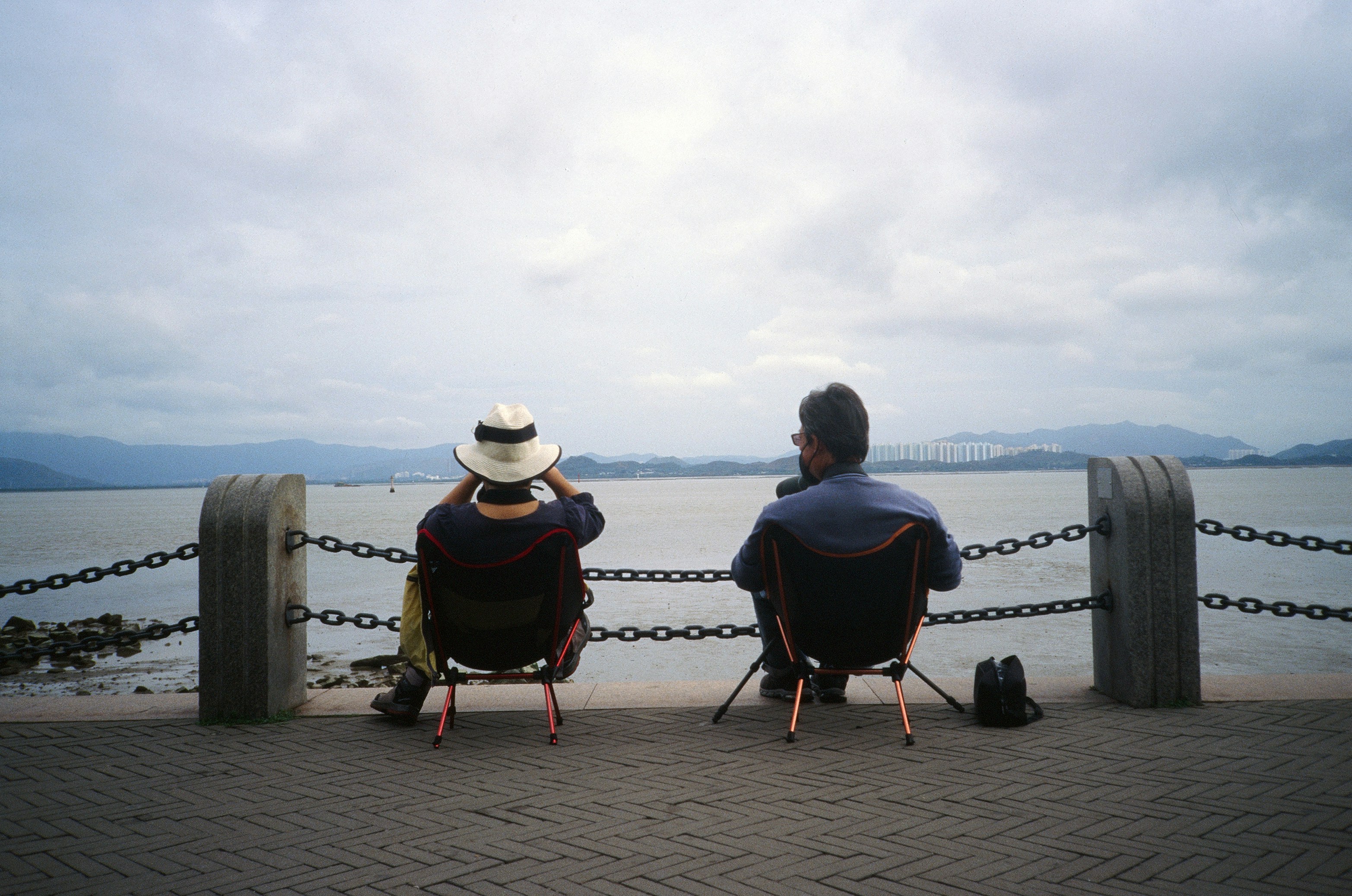 Dos personas se sientan en sillas mirando al agua.