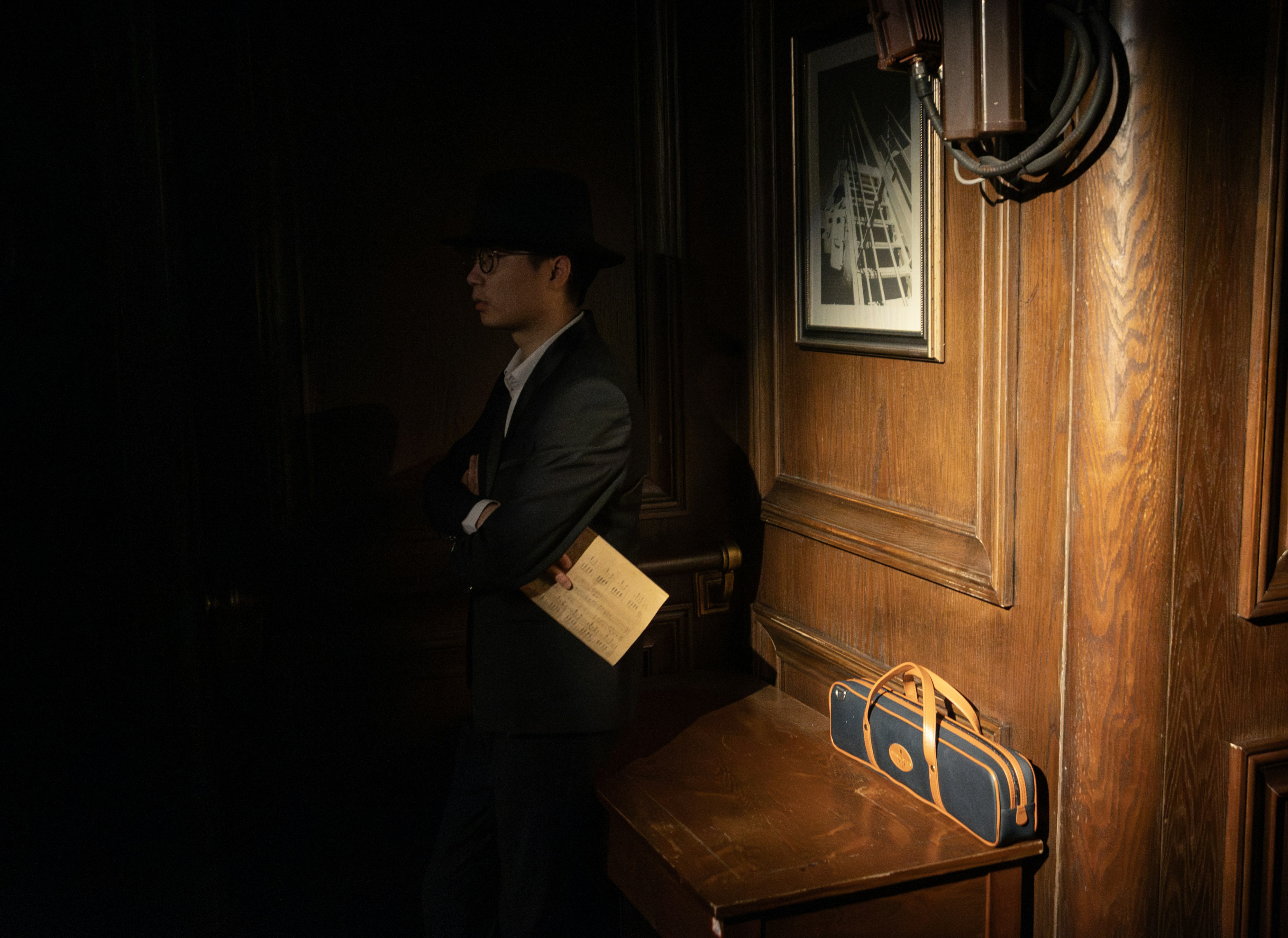 Man in suit and hat holding a letter indoors.