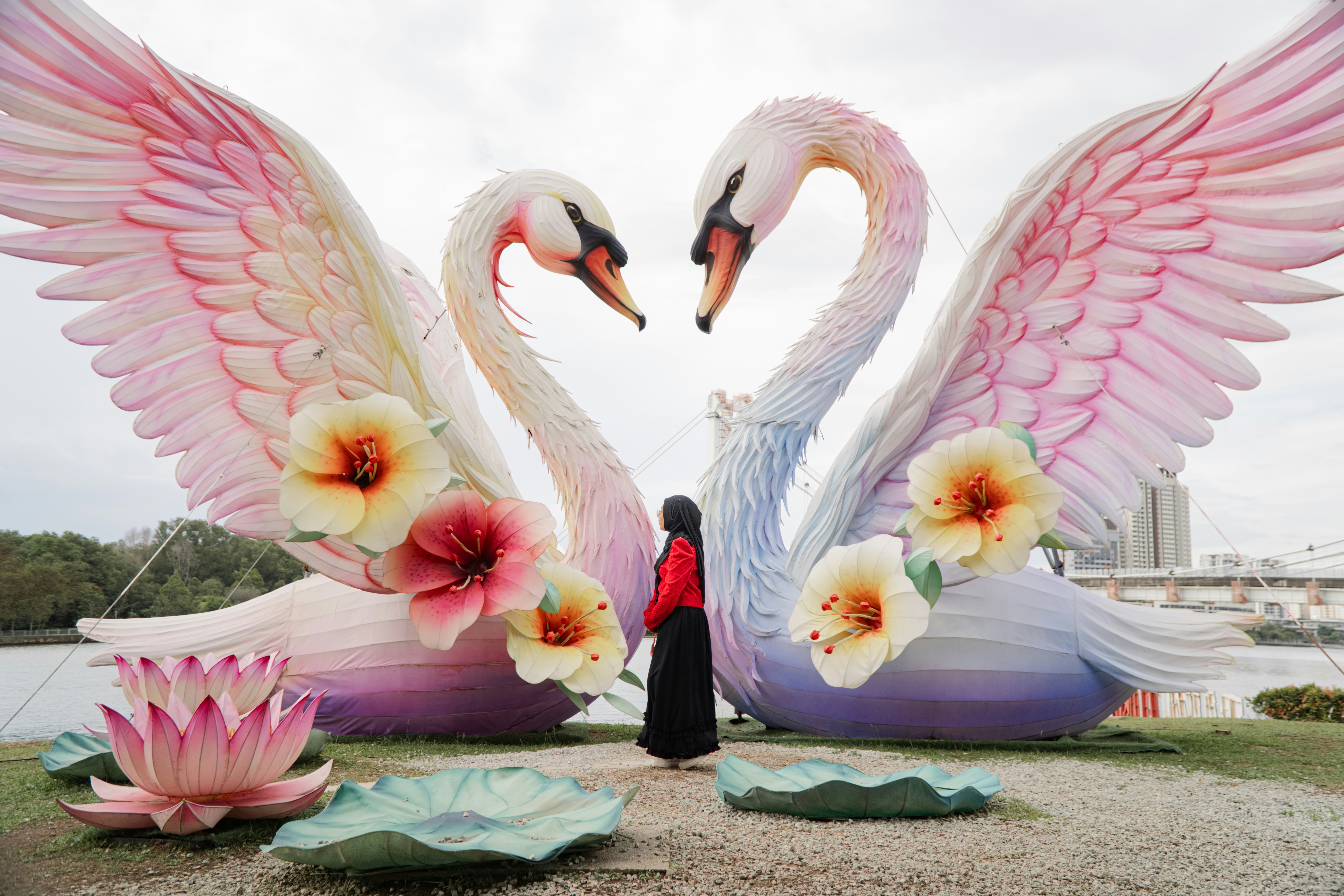 Two large swan sculptures with a person standing between them