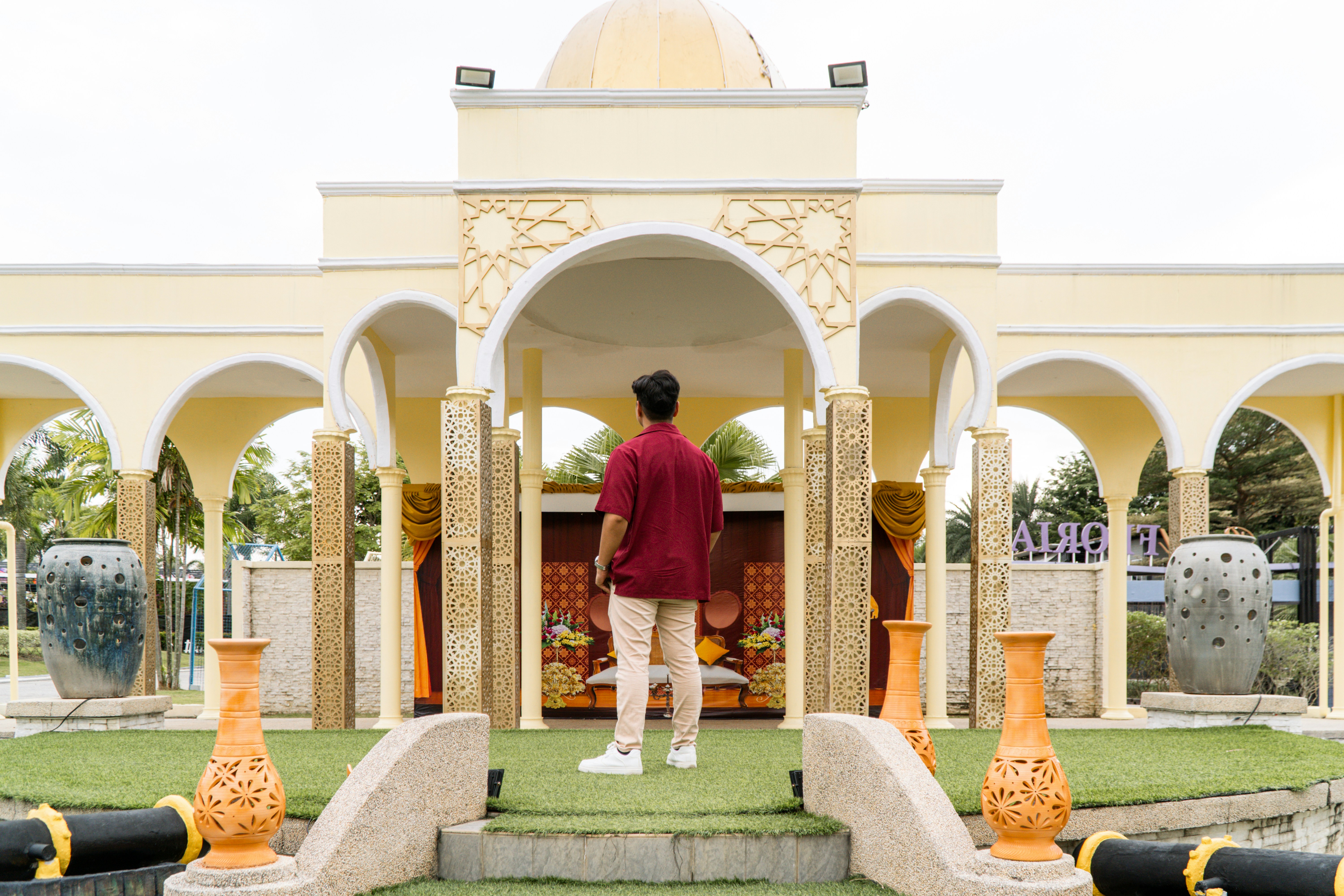Man in maroon shirt stands before ornate building