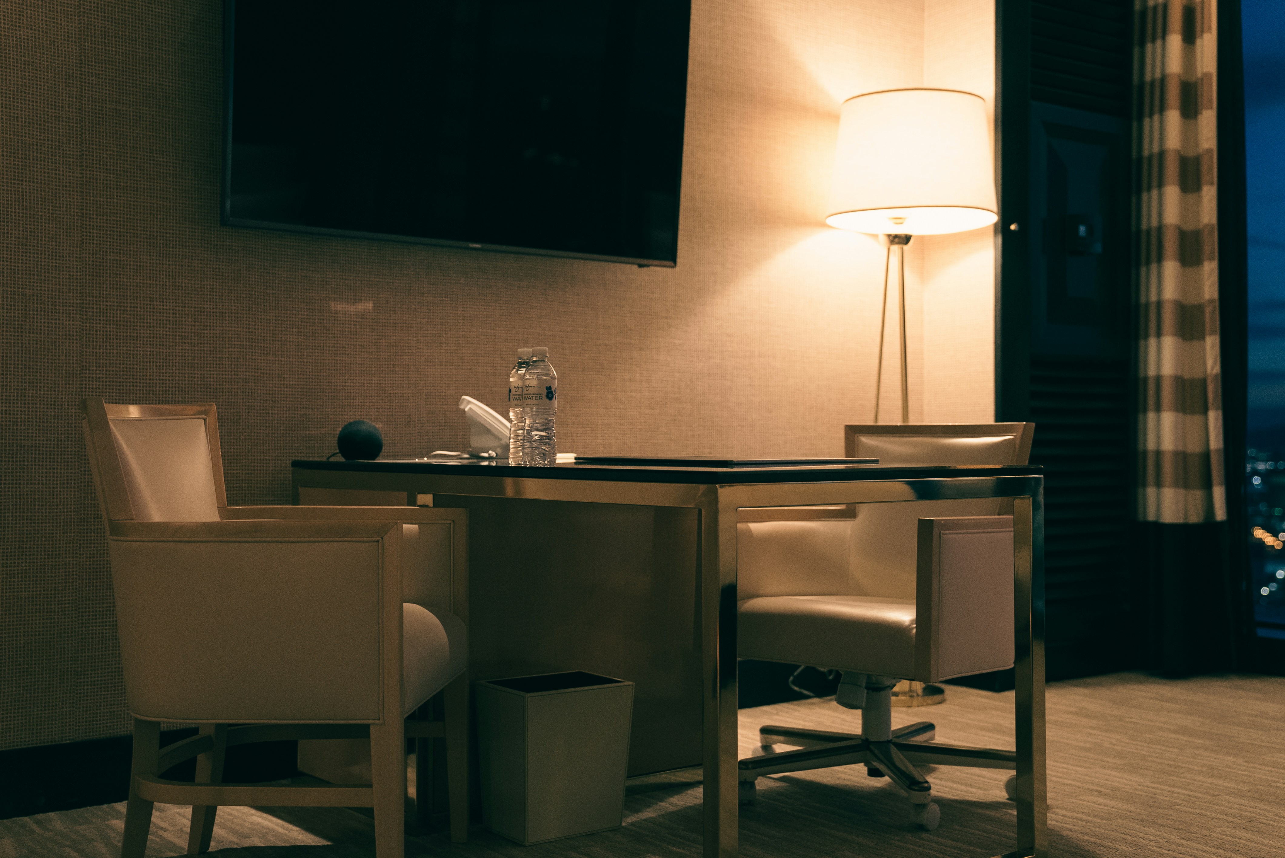 Desk with chairs and lamp in a dimly lit room.