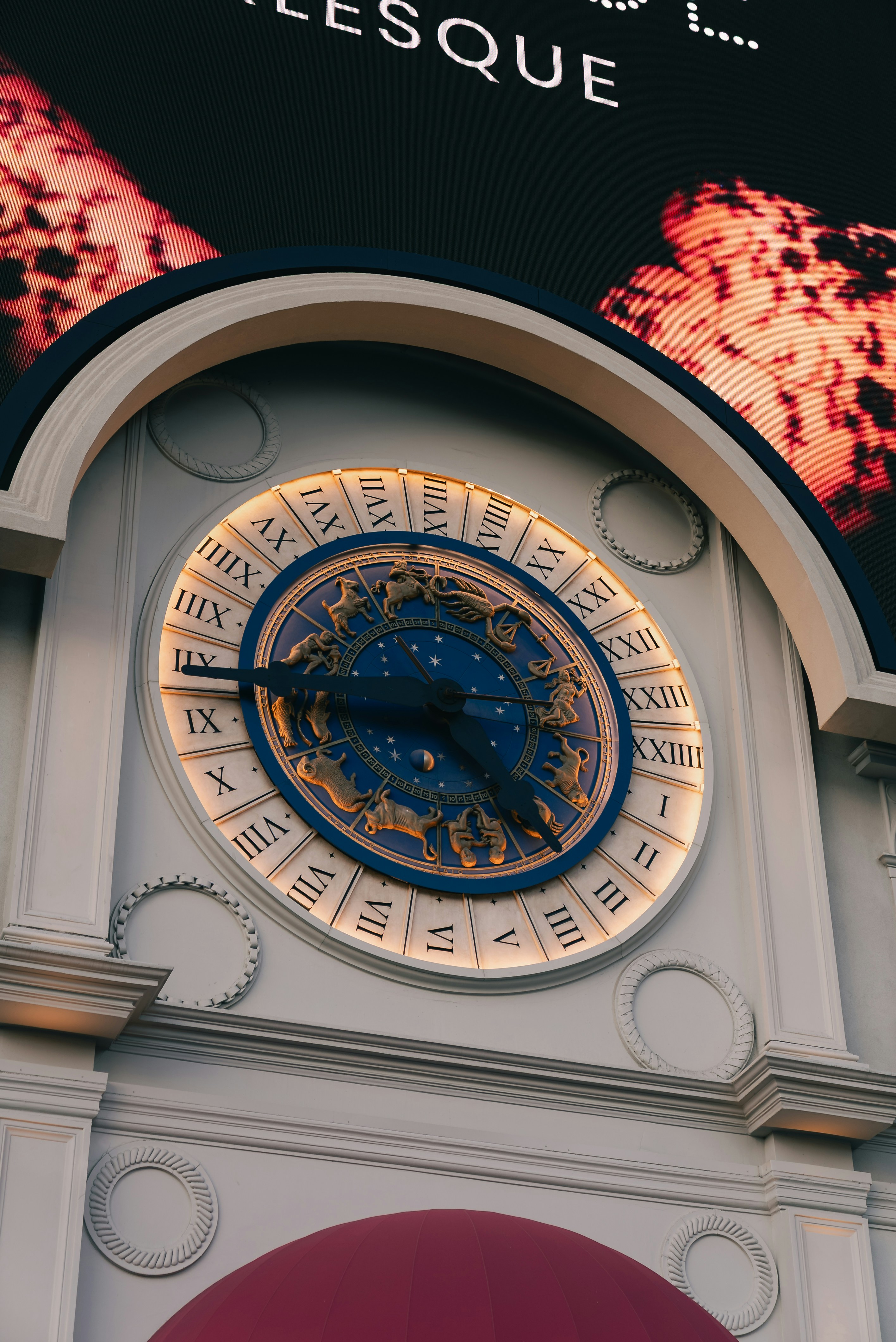 Carátula de reloj ornamentada con números romanos y símbolos del zodiaco