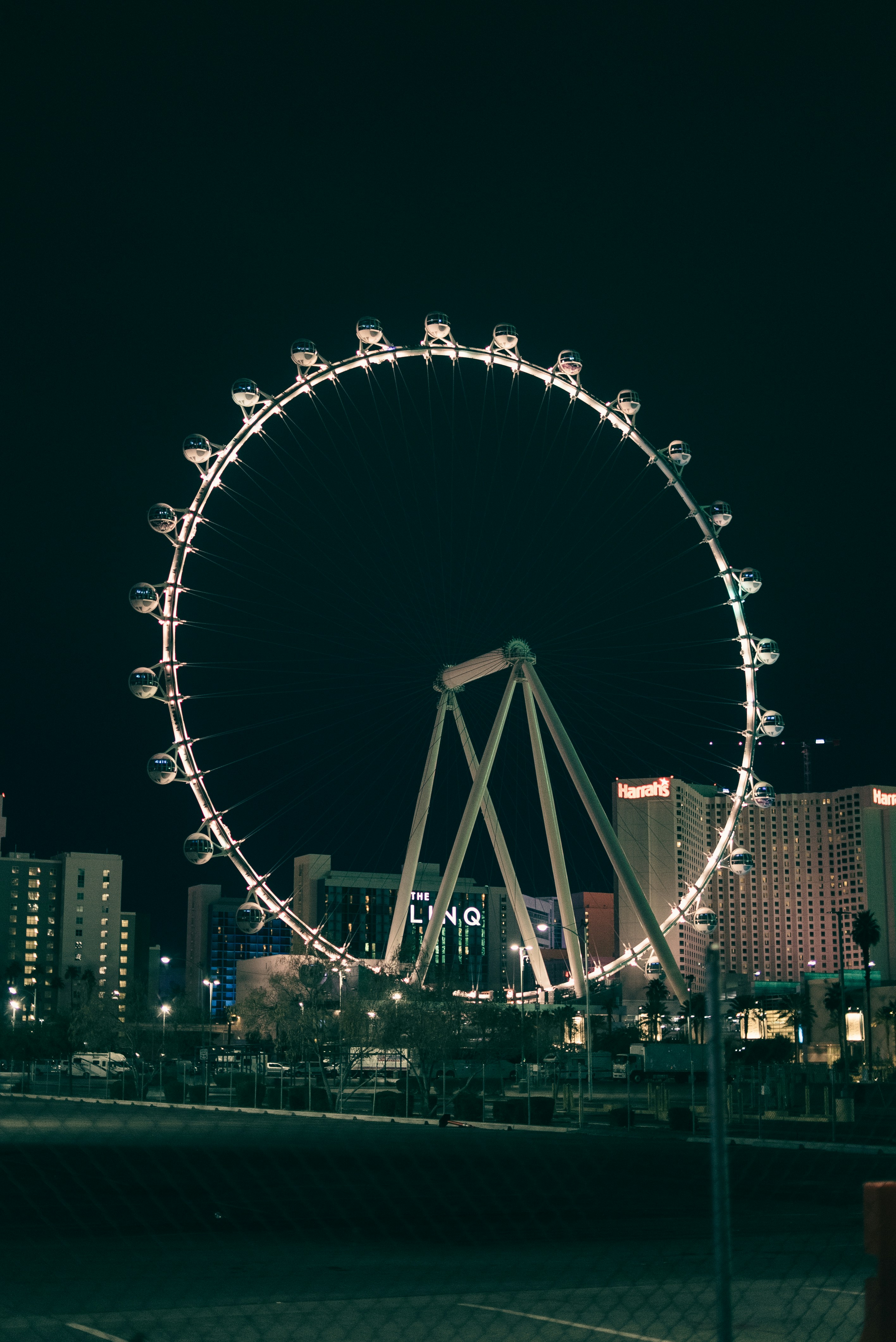 A brightly lit ferris wheel at night with city buildings.
