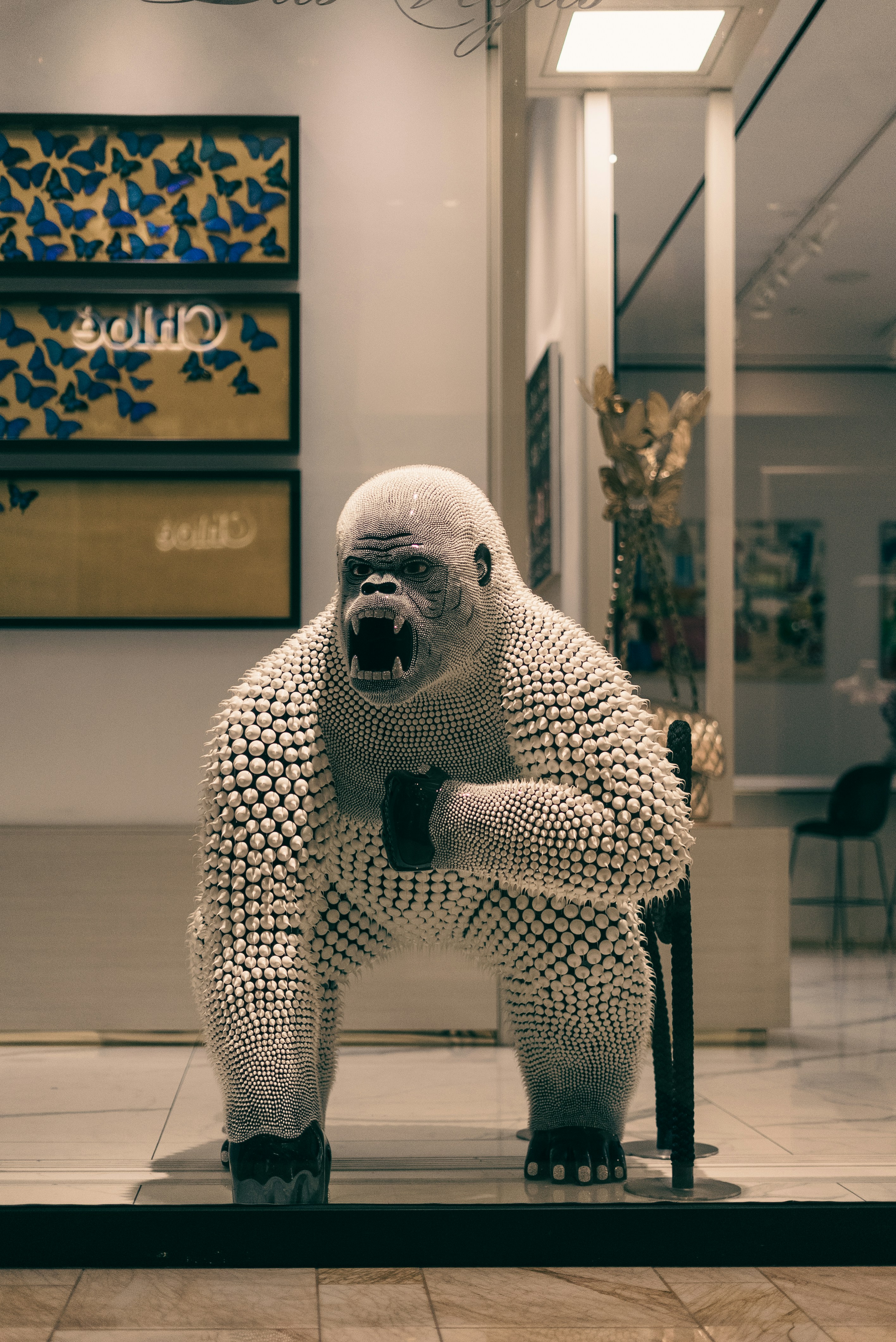 Escultura de gorila blanca con la boca abierta y los puños apretados
