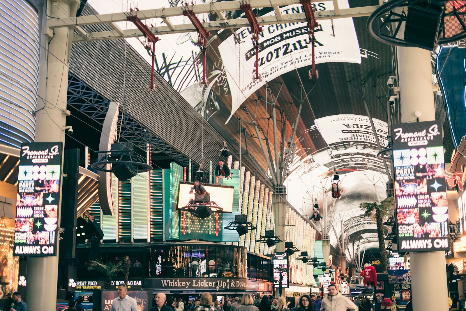 Visitors stroll beneath the arched LED canopy of Fremont Street in downtown Las Vegas as zip-line riders pass overhead