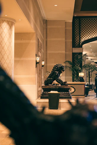 A lion statue in a hotel lobby with palm trees.