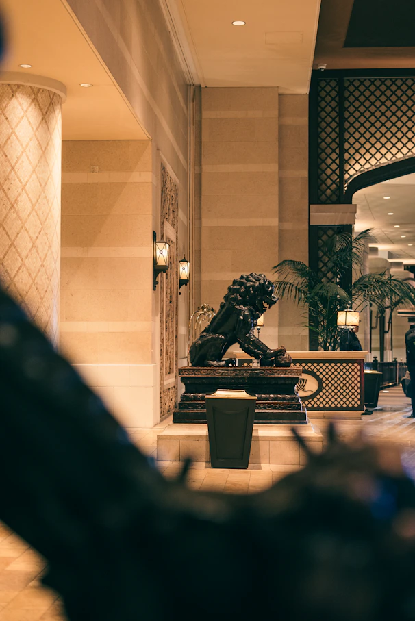 A lion statue in a hotel lobby with palm trees.