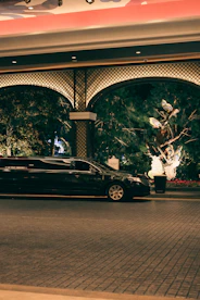 A black limousine parked outside an ornate building entrance.