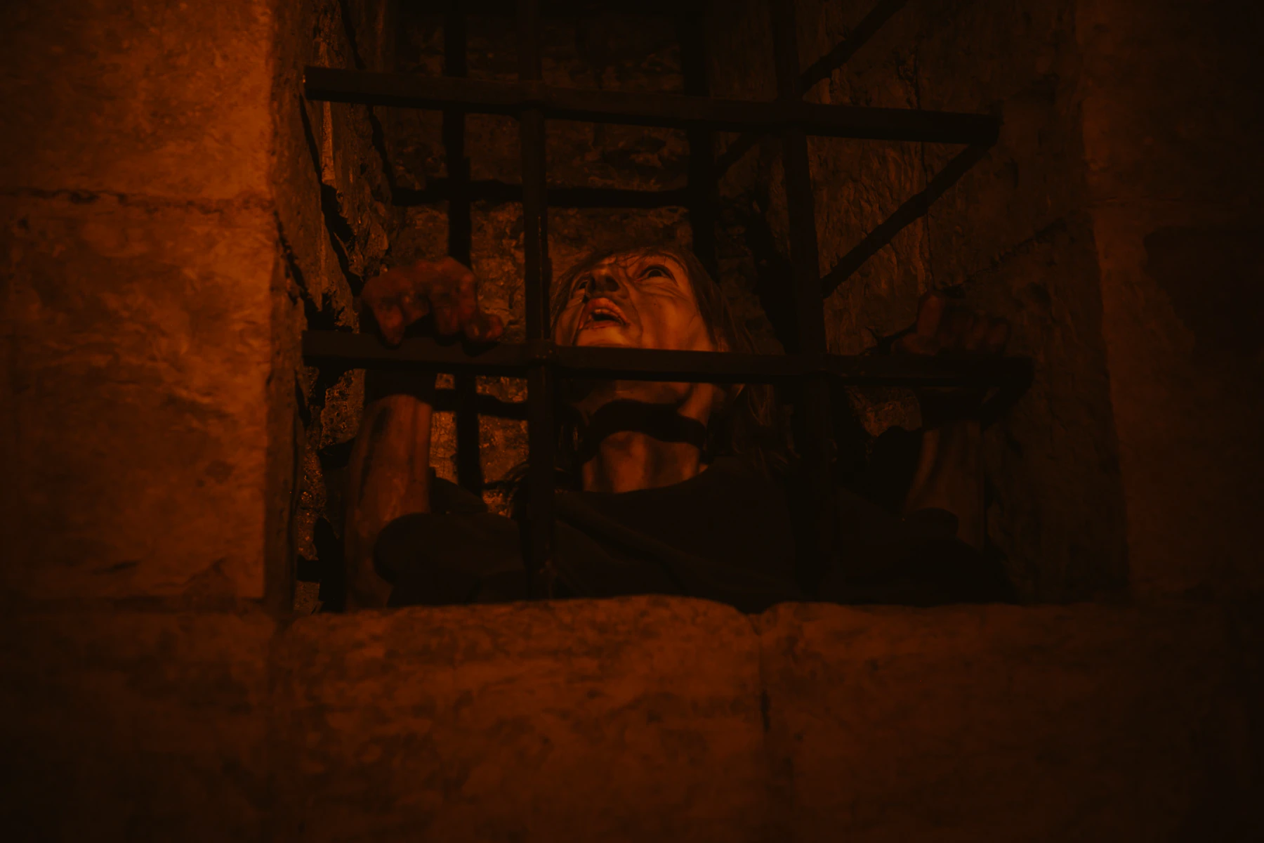 A Person Partly Visible Behind Prison Bars In Darkness