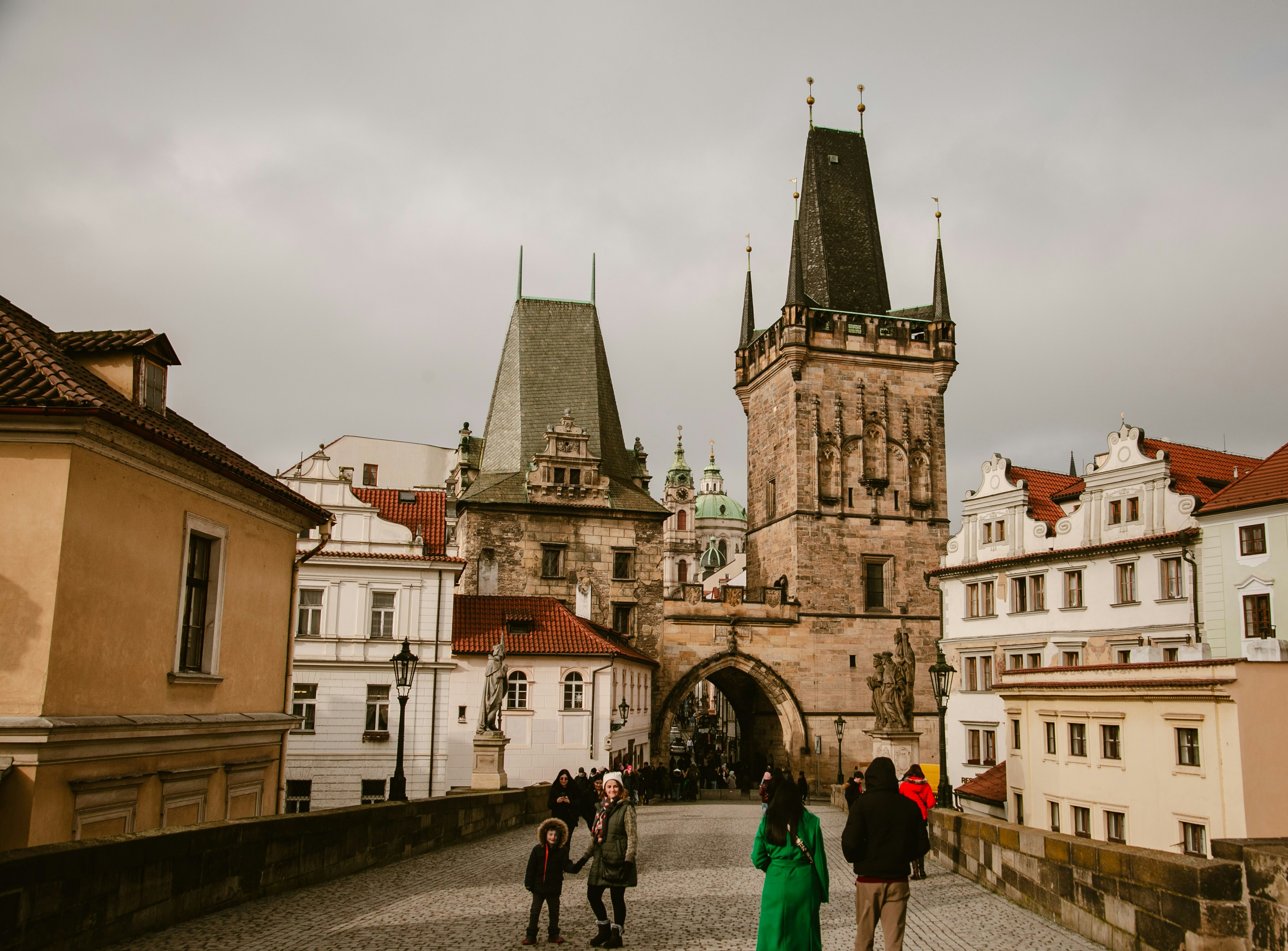 People walking on a historic bridge with towers.