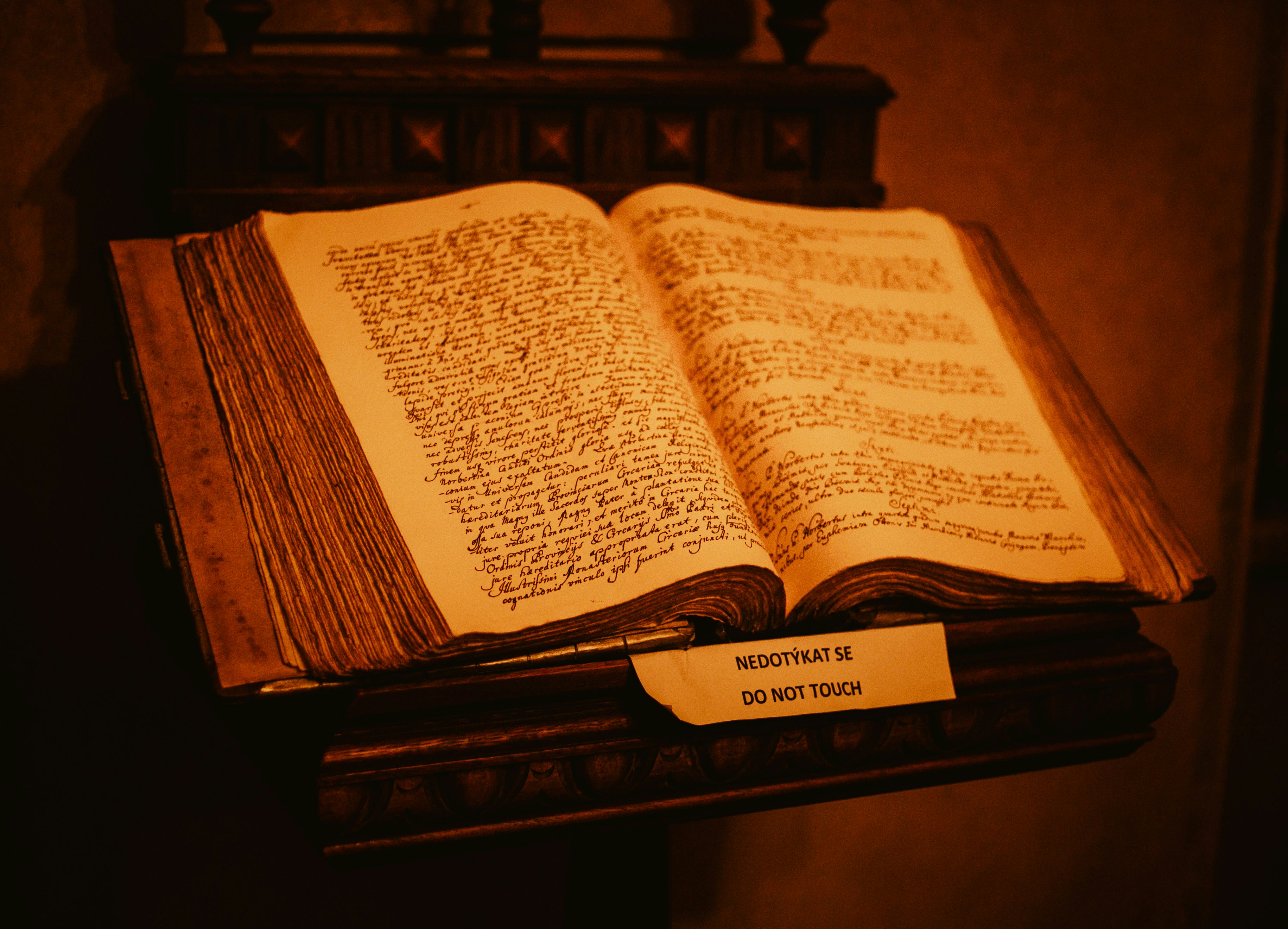 An old open book rests on a wooden stand.