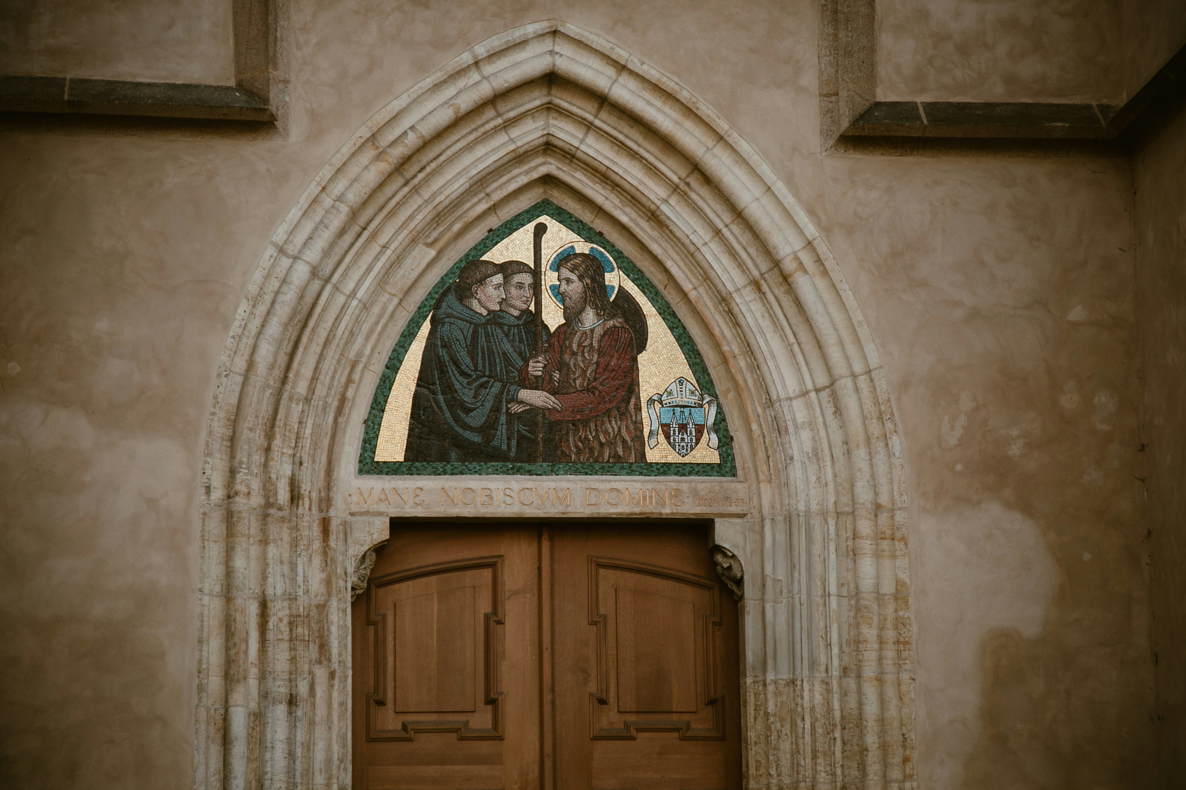 Mosaic above wooden doors on stone building