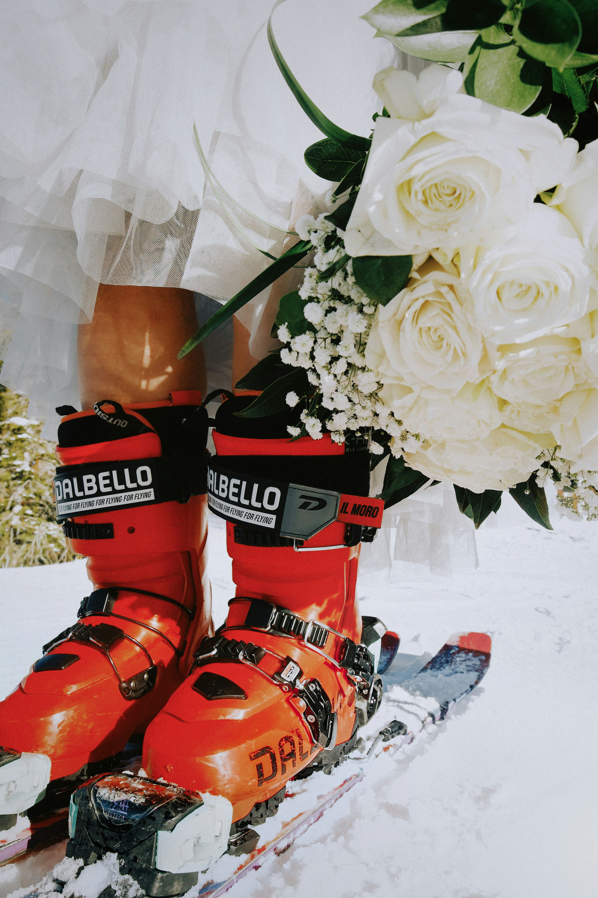 Rote Skischuhe und Ski auf Schnee mit Rosen