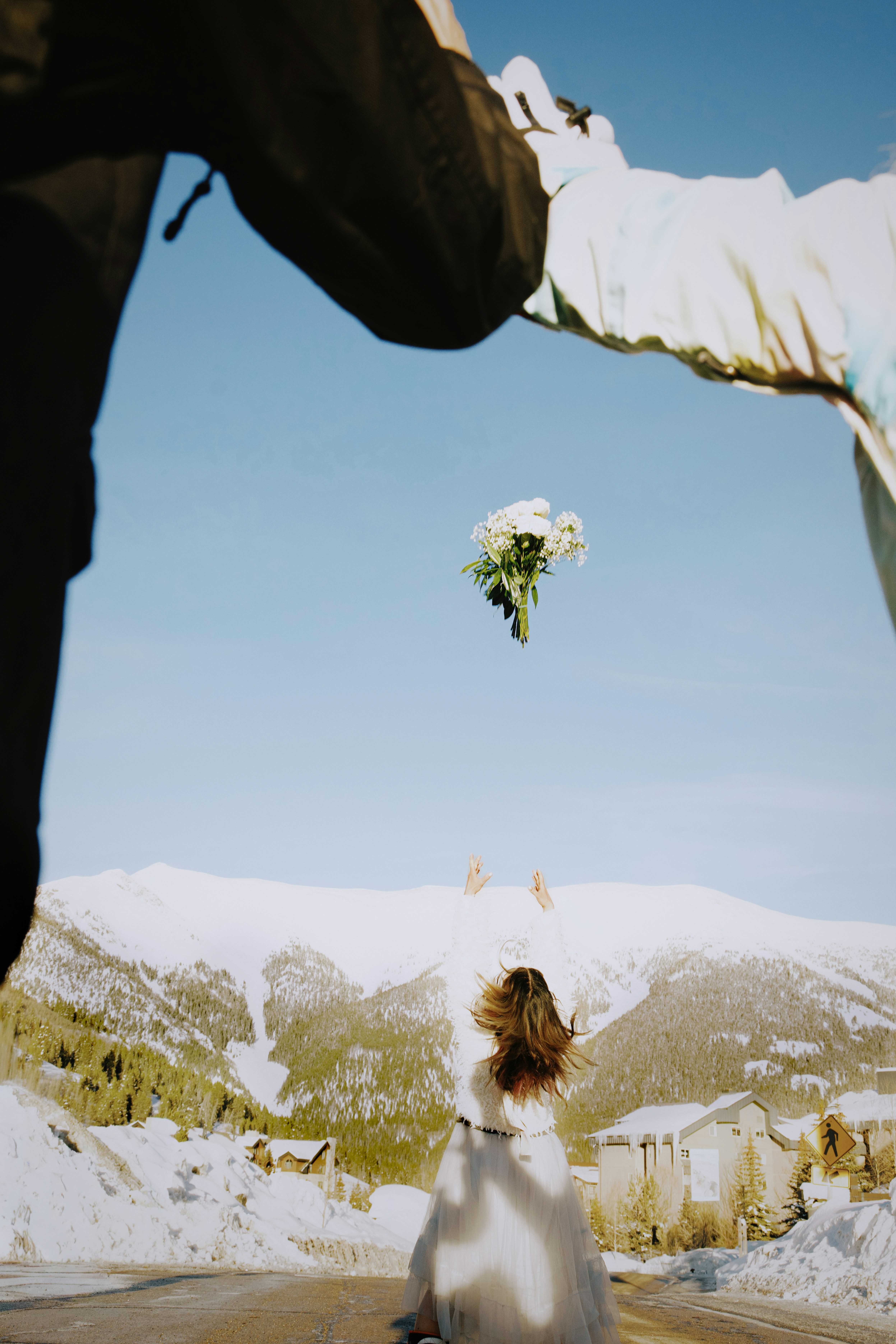 Bride throws bouquet with snowy mountains background