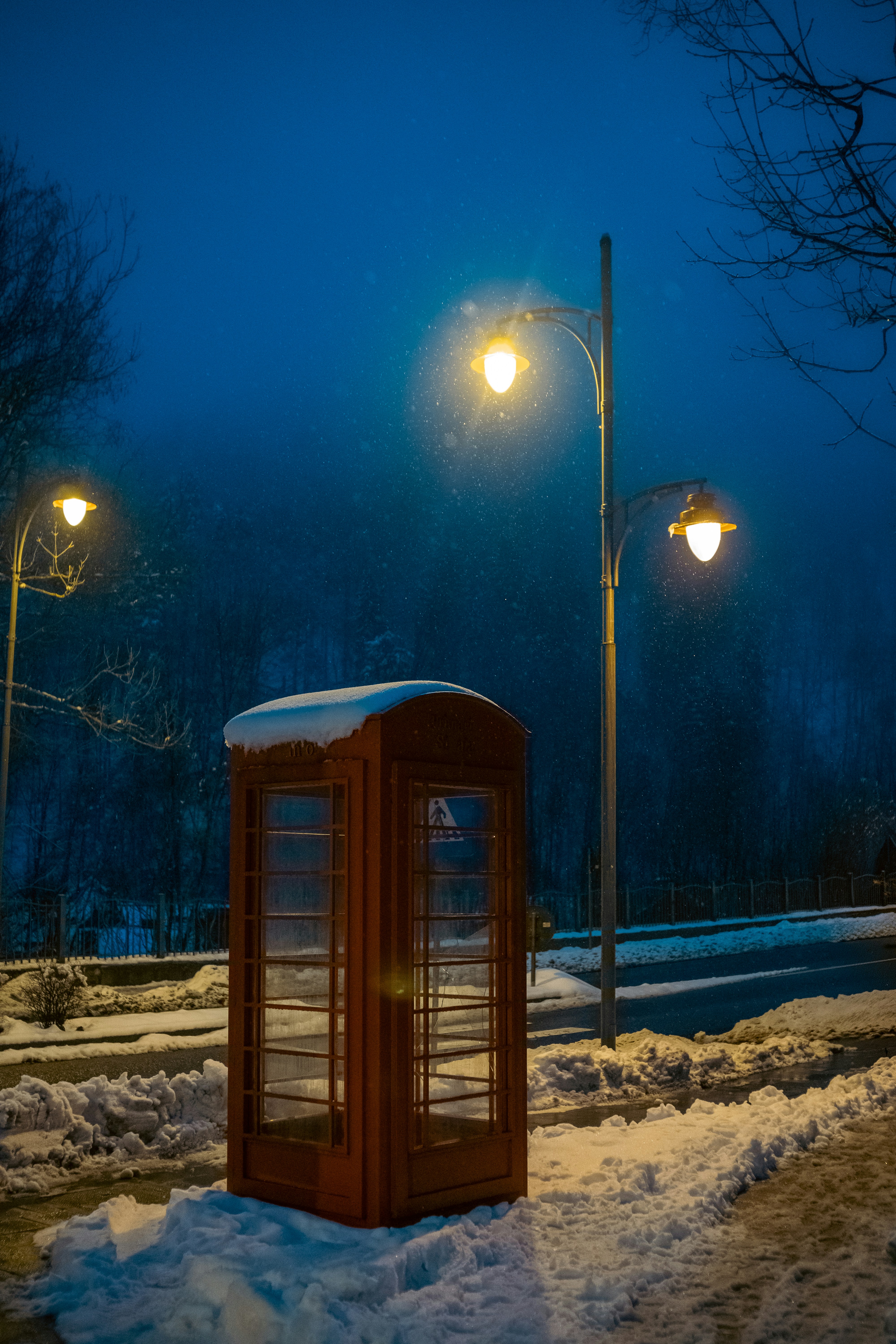 Red telephone booth in snowy night with streetlights