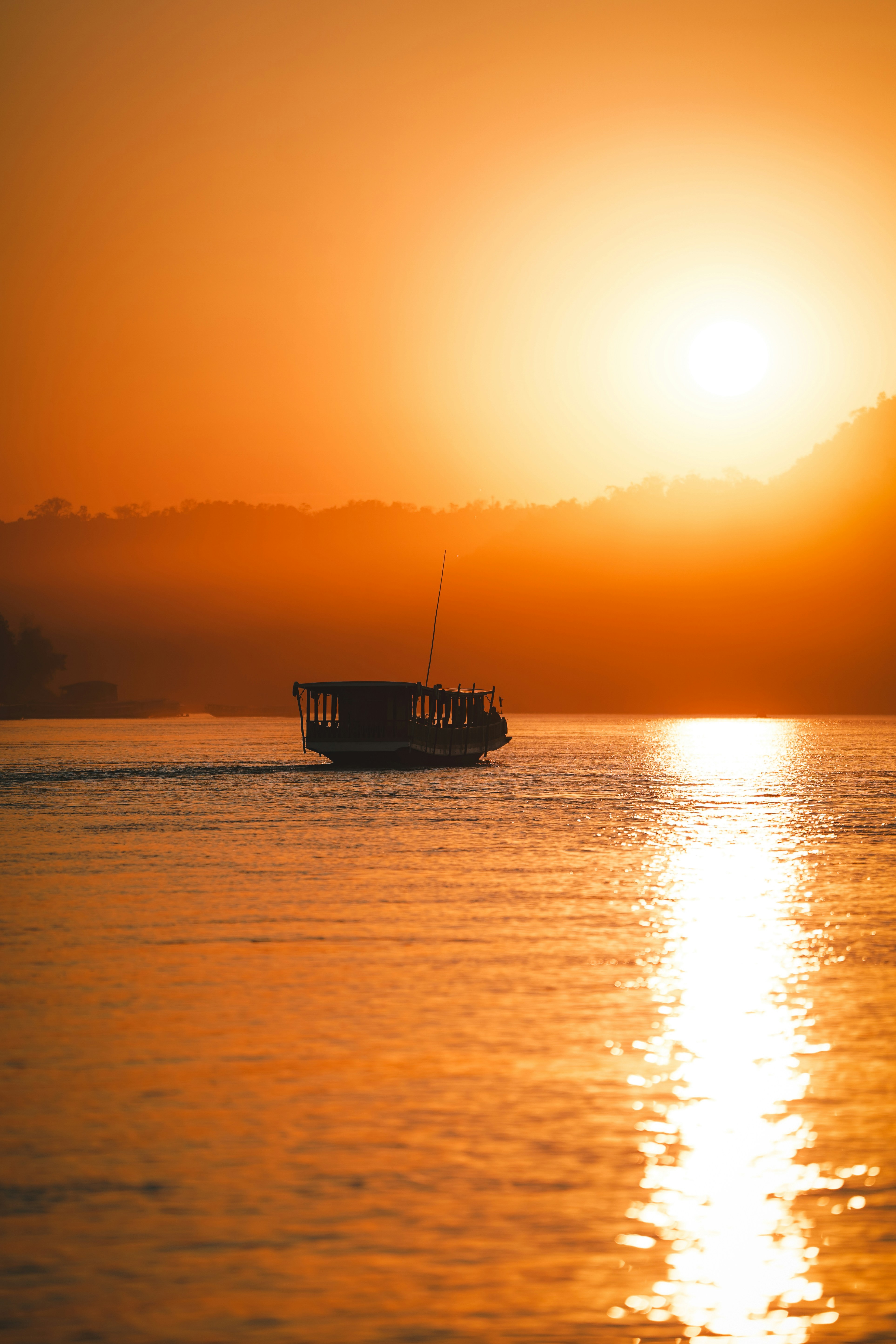 A boat sails on the water at sunset